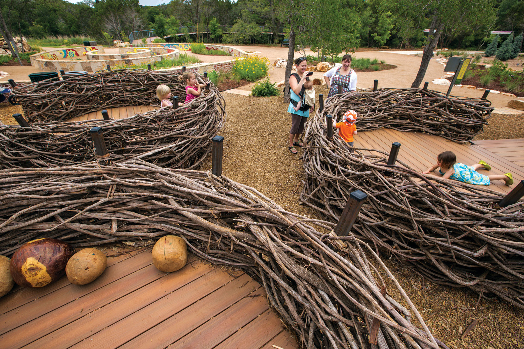 Families with small children stand inside human-scaled birds nests at the Lady Bird Johnson Wildflower Center's Family Garden