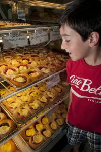 A young boy in a red shirt admires the case of fruit-filled kolaches at Czech Stop in West, Texas.