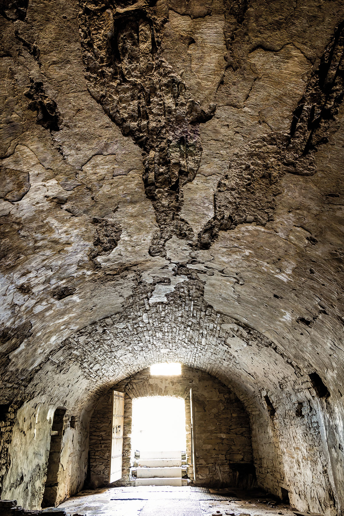 The interior of a dark gray cavern with a light at the end