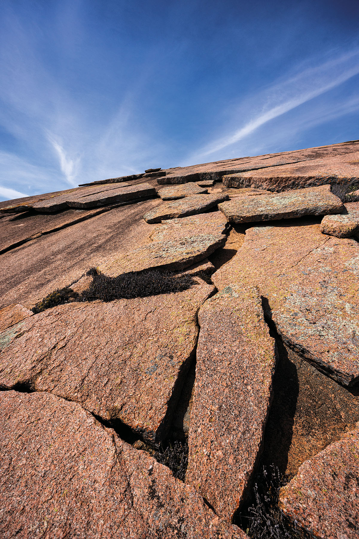 Large chunks of flat red rock sit on a hillside under bright blue sky