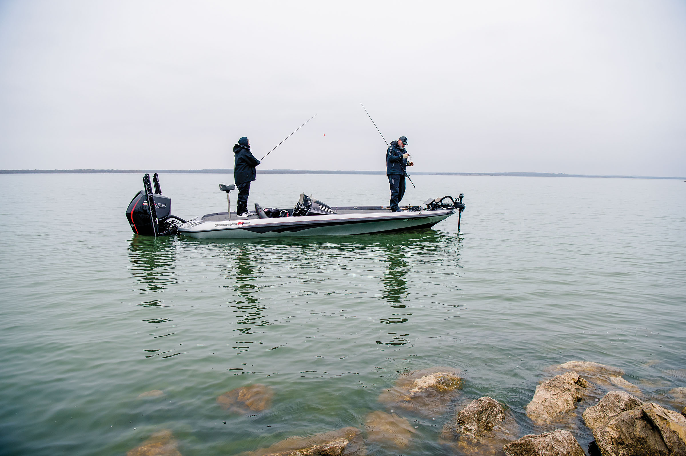 Two people stand in a boat on a foggy day on green water