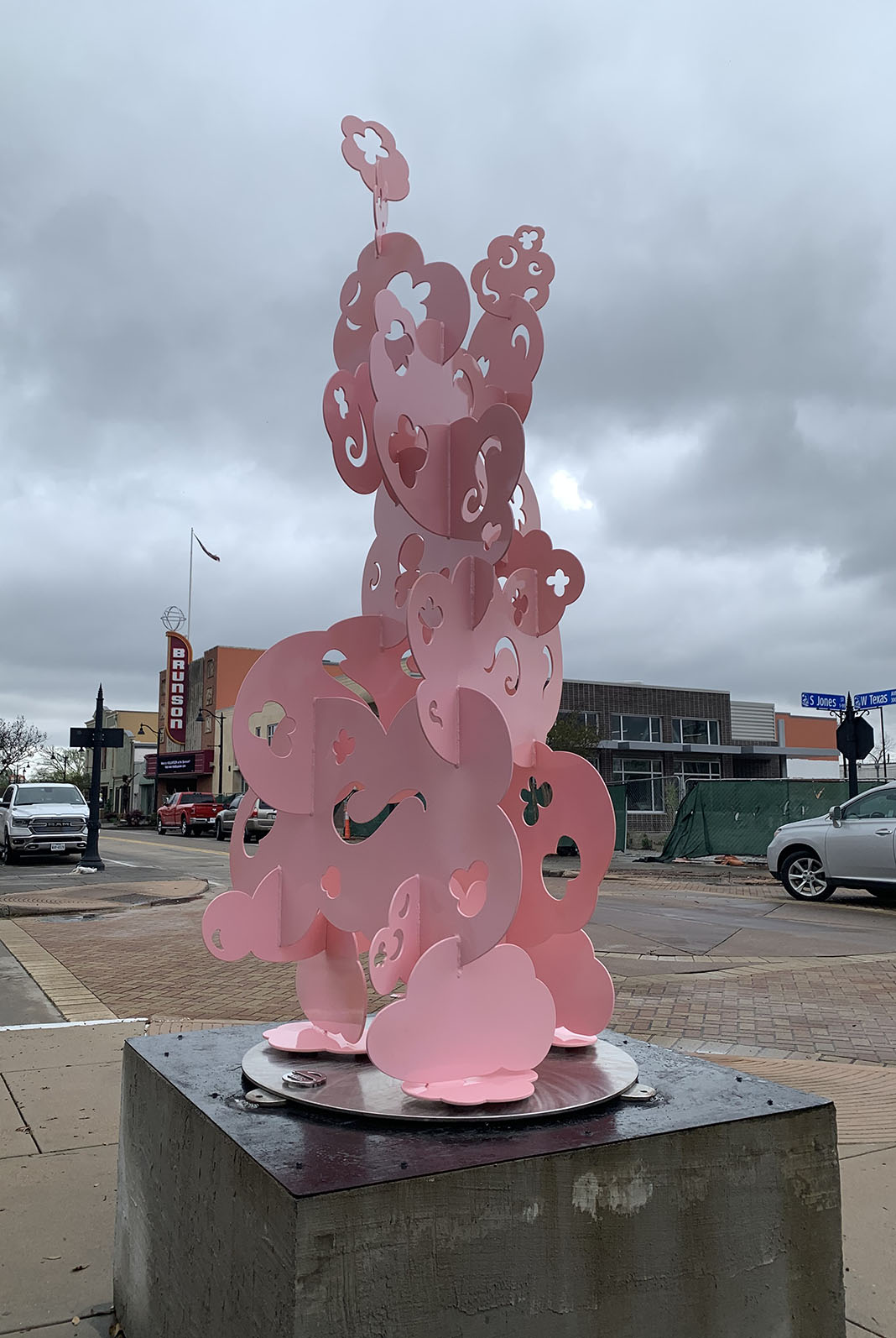 A pink sculpture with many loops and designs on a cloudy gray day