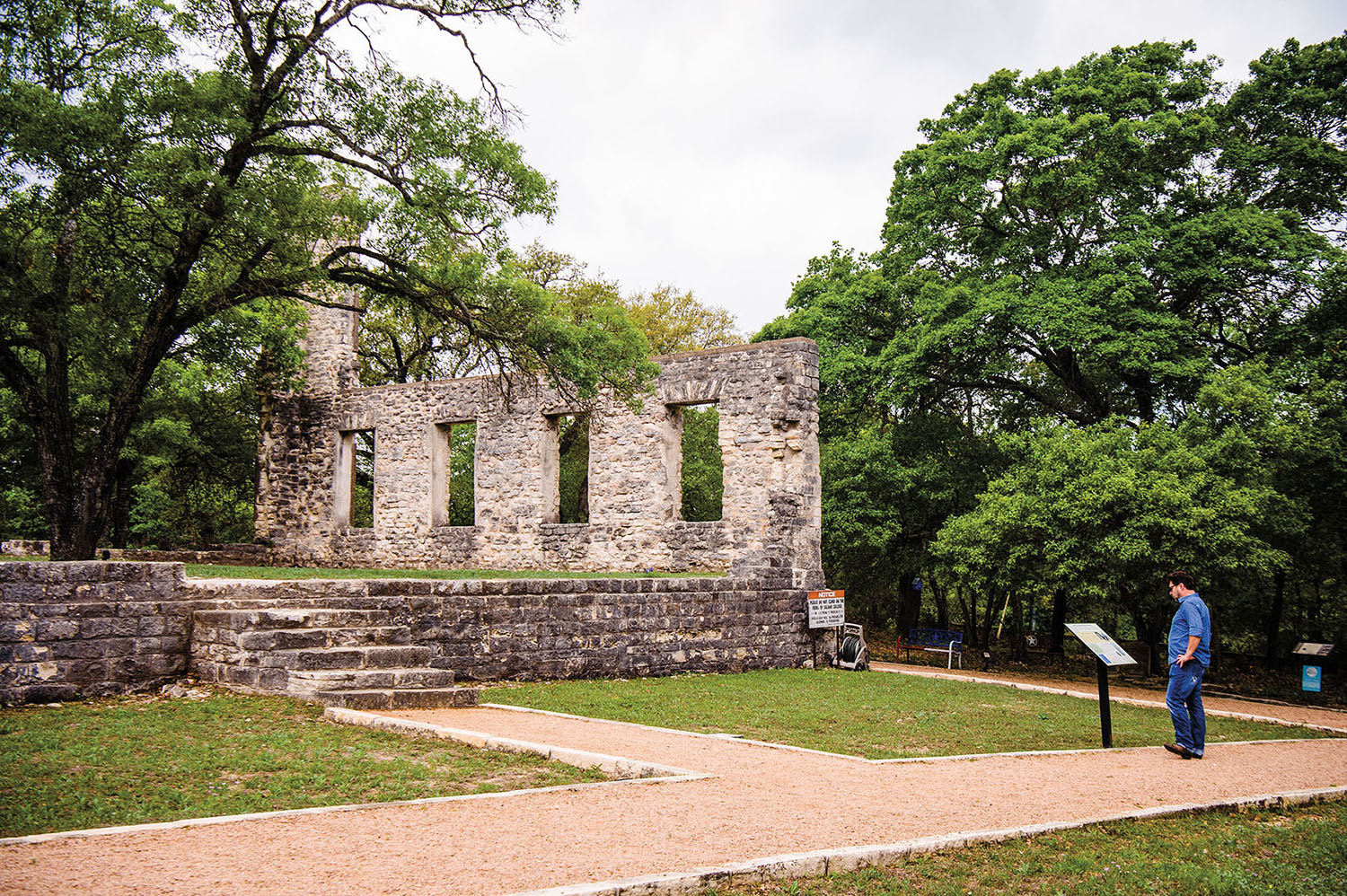 The exterior of a stone building in a green wooded area