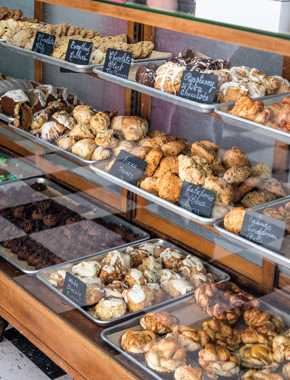A bakery display case with numerous pastries and treats along with chalkboard labels