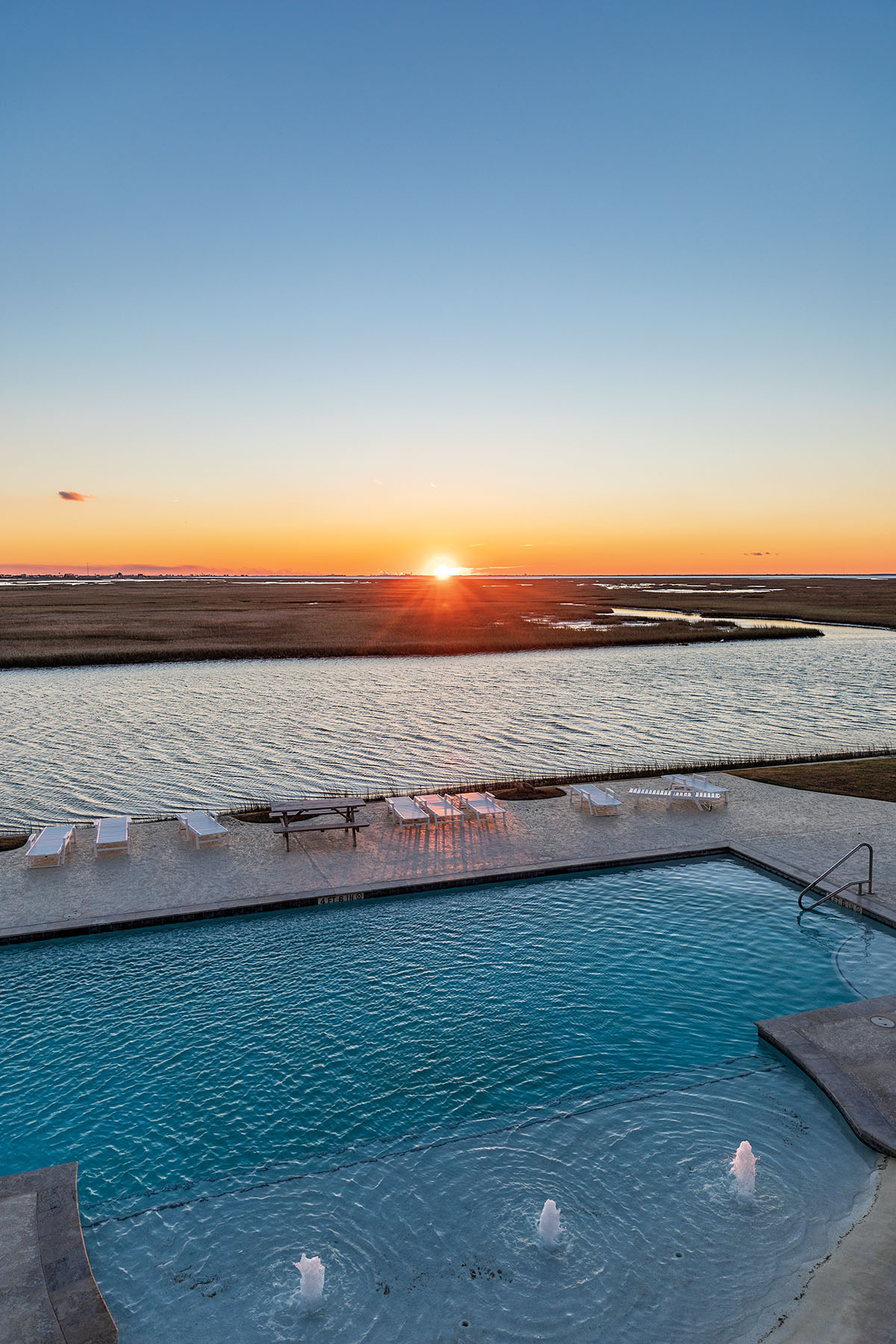 The sun sets behind a clear blue pool 