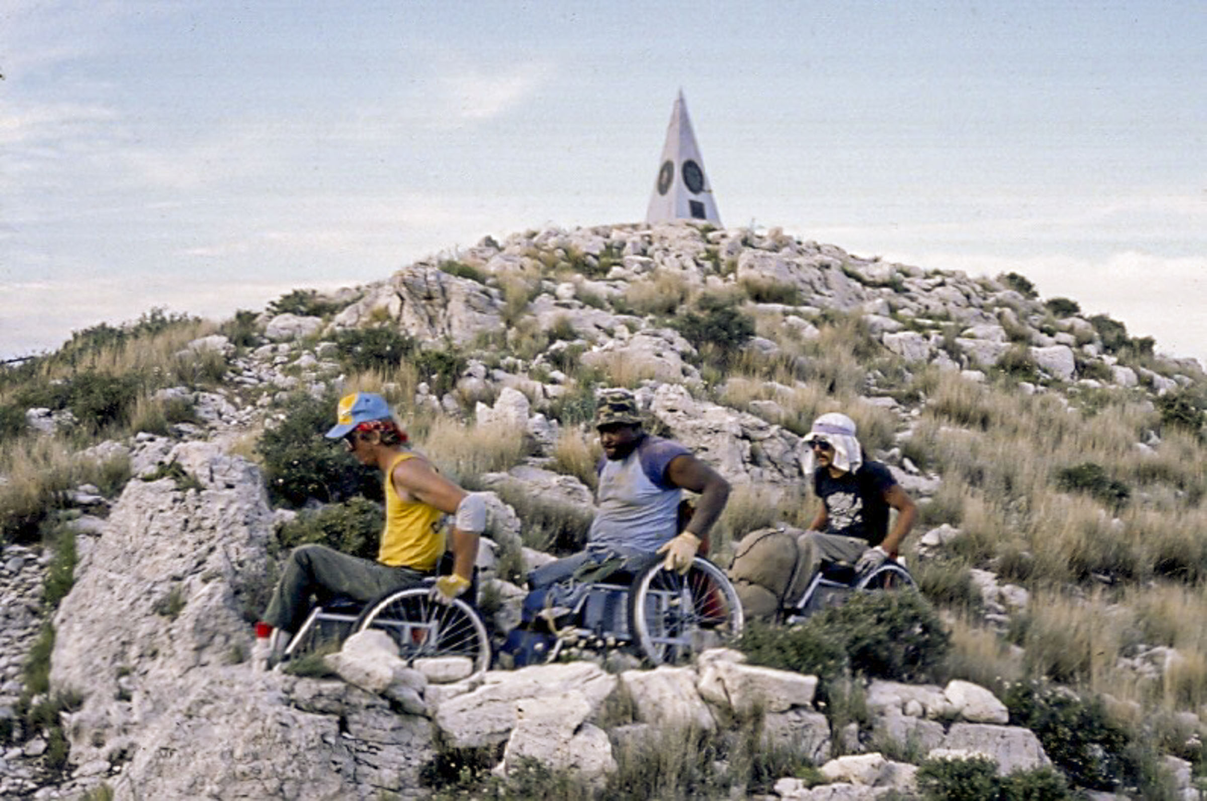 Three men carefully taverse rocky terrain near the top of Guadalupe Peak