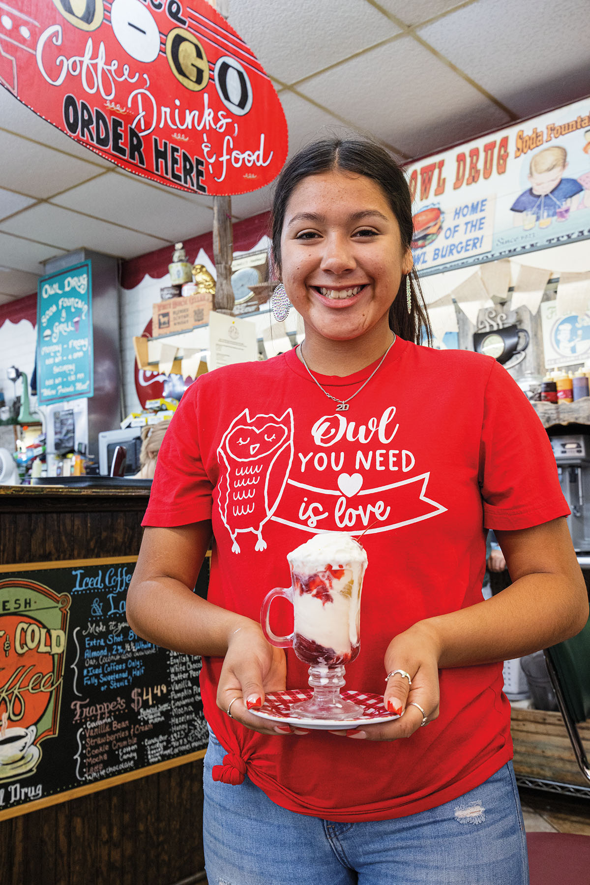 A woman wearing a bright red shirt reading "Owl you need is love"