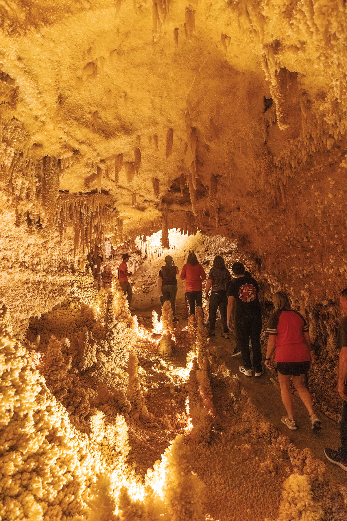 A group of people walk through a golden-colored cavern with large rock outcroppings