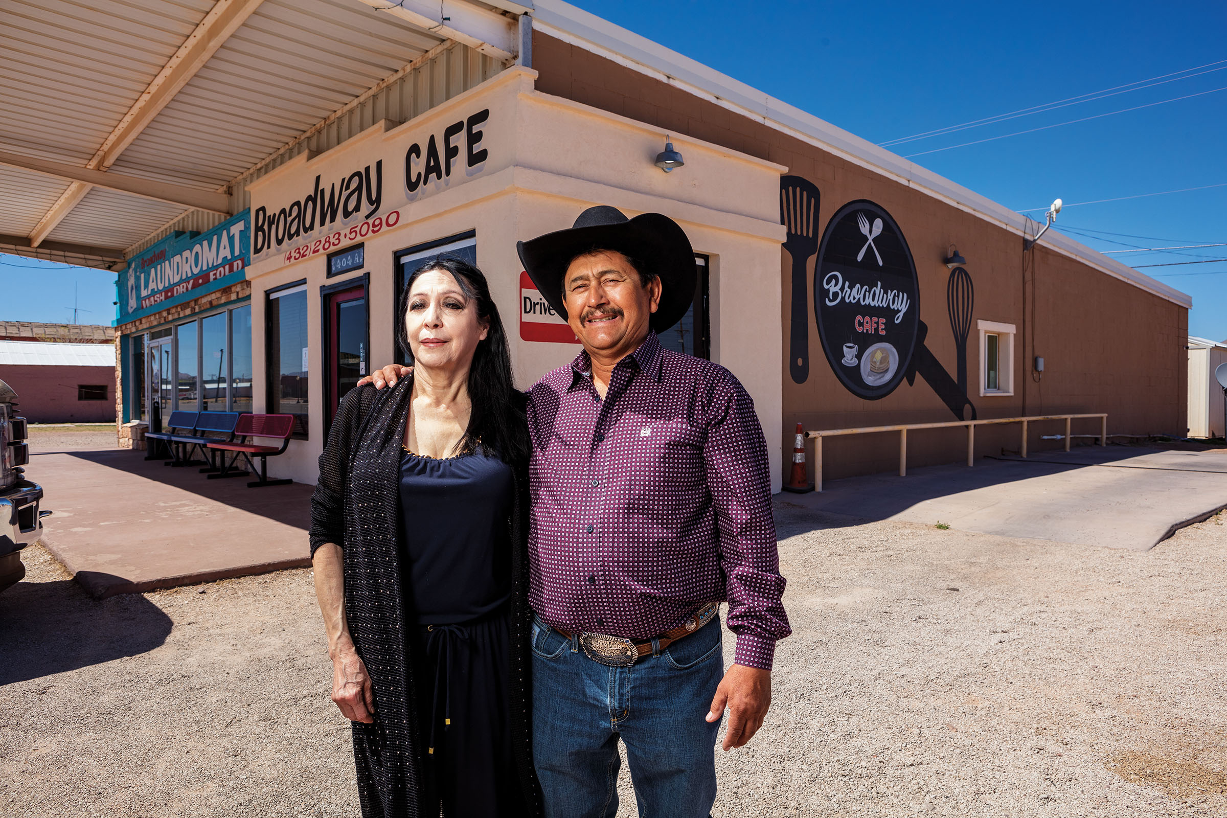 A man and woman stand in front of a restaurant