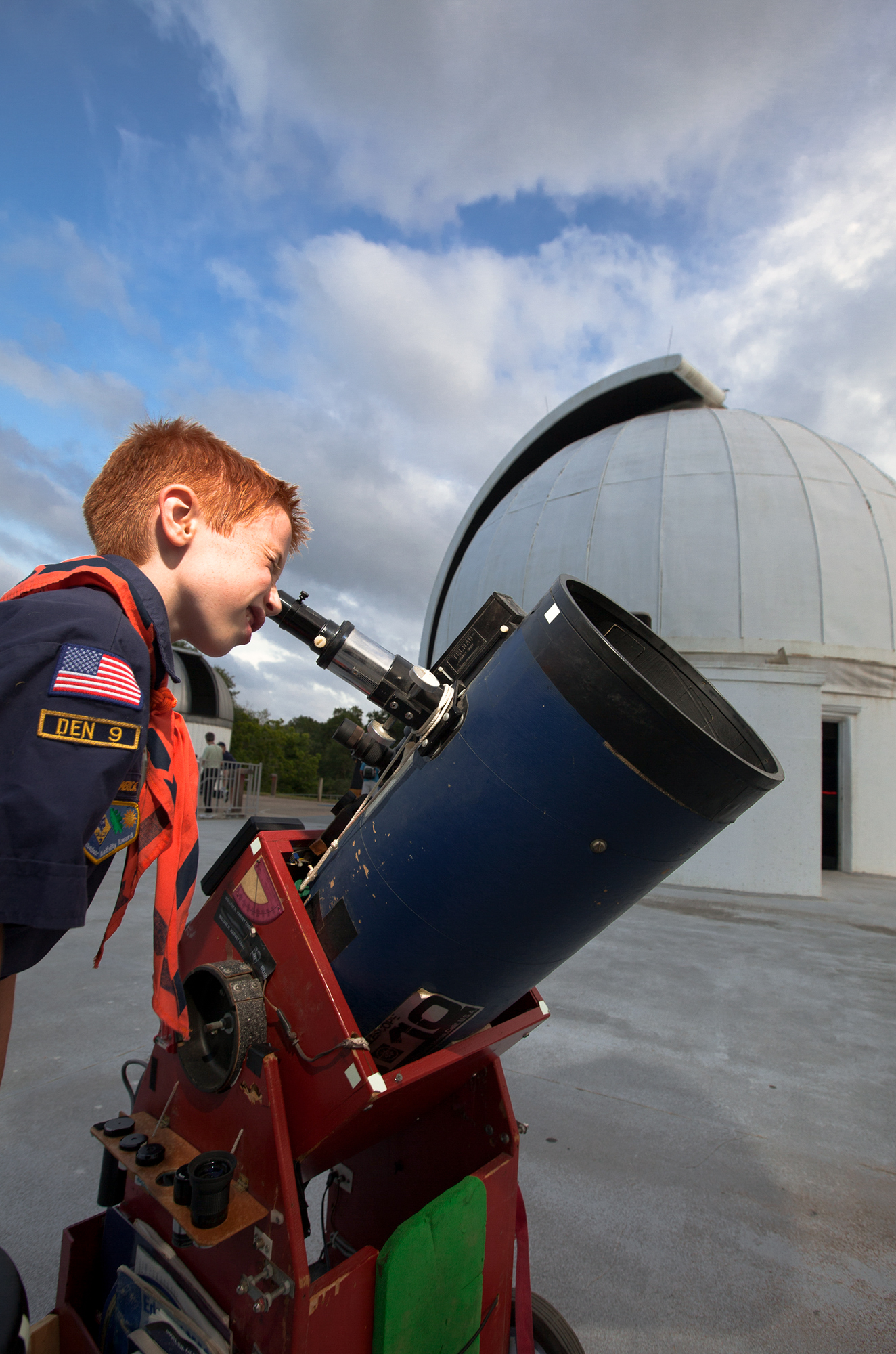 A child in a scout uniform looks through a telescope at the George Observatory