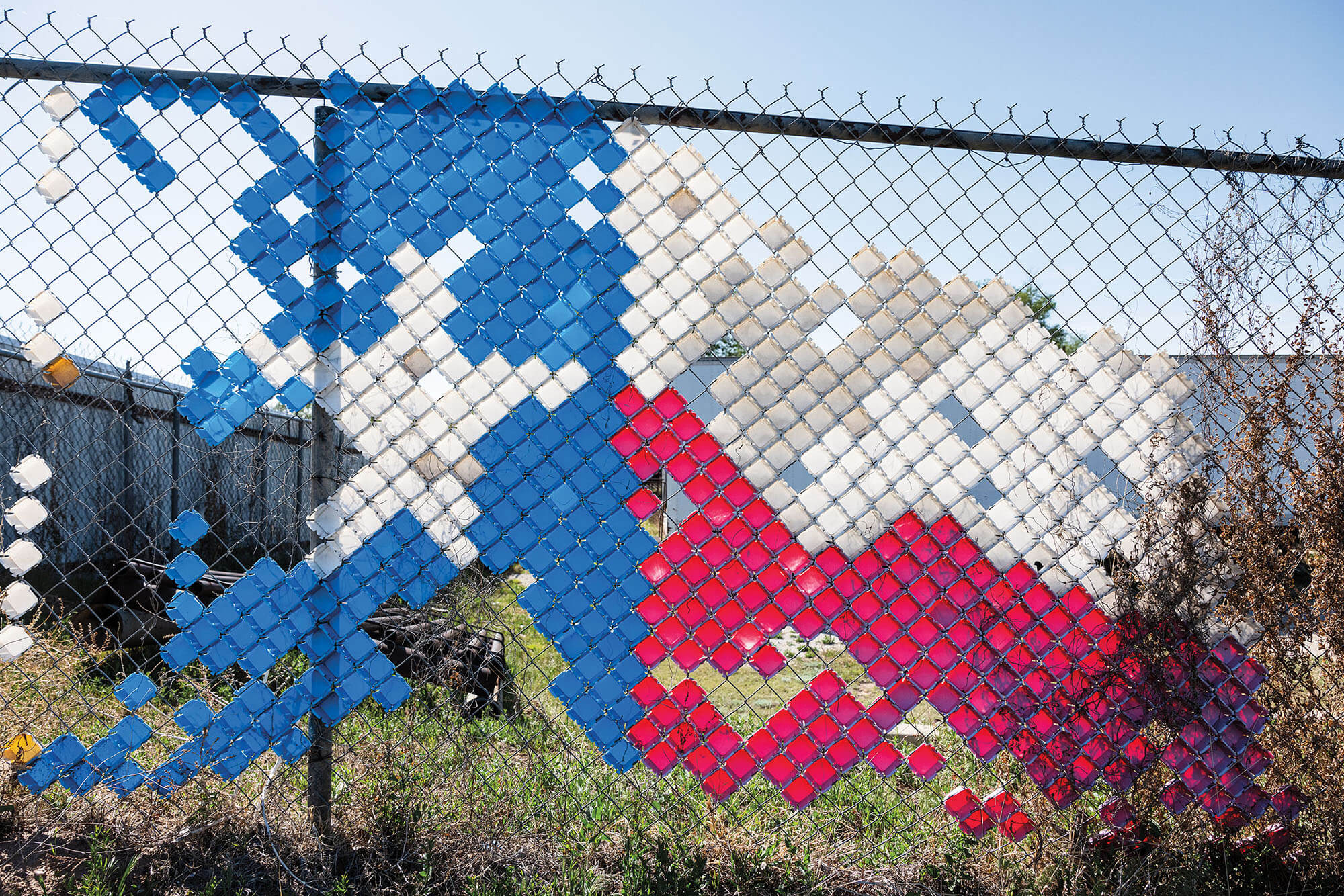 A chain-link fence decorated with the Texas flag 