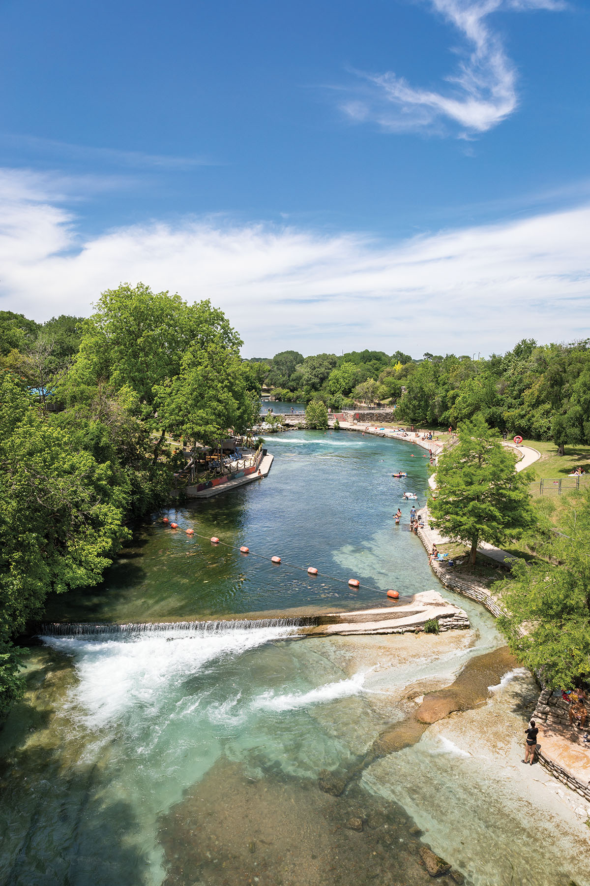 An overhead view of a large clear river with a rope across and a small rock chute visible in one corner