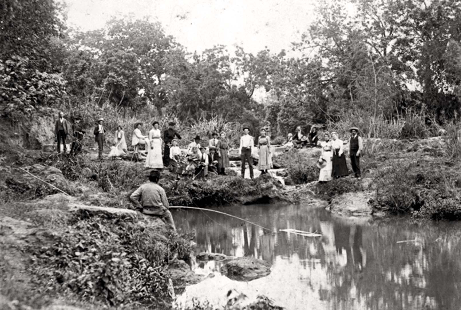 A historic photograph of people standing around a body of water