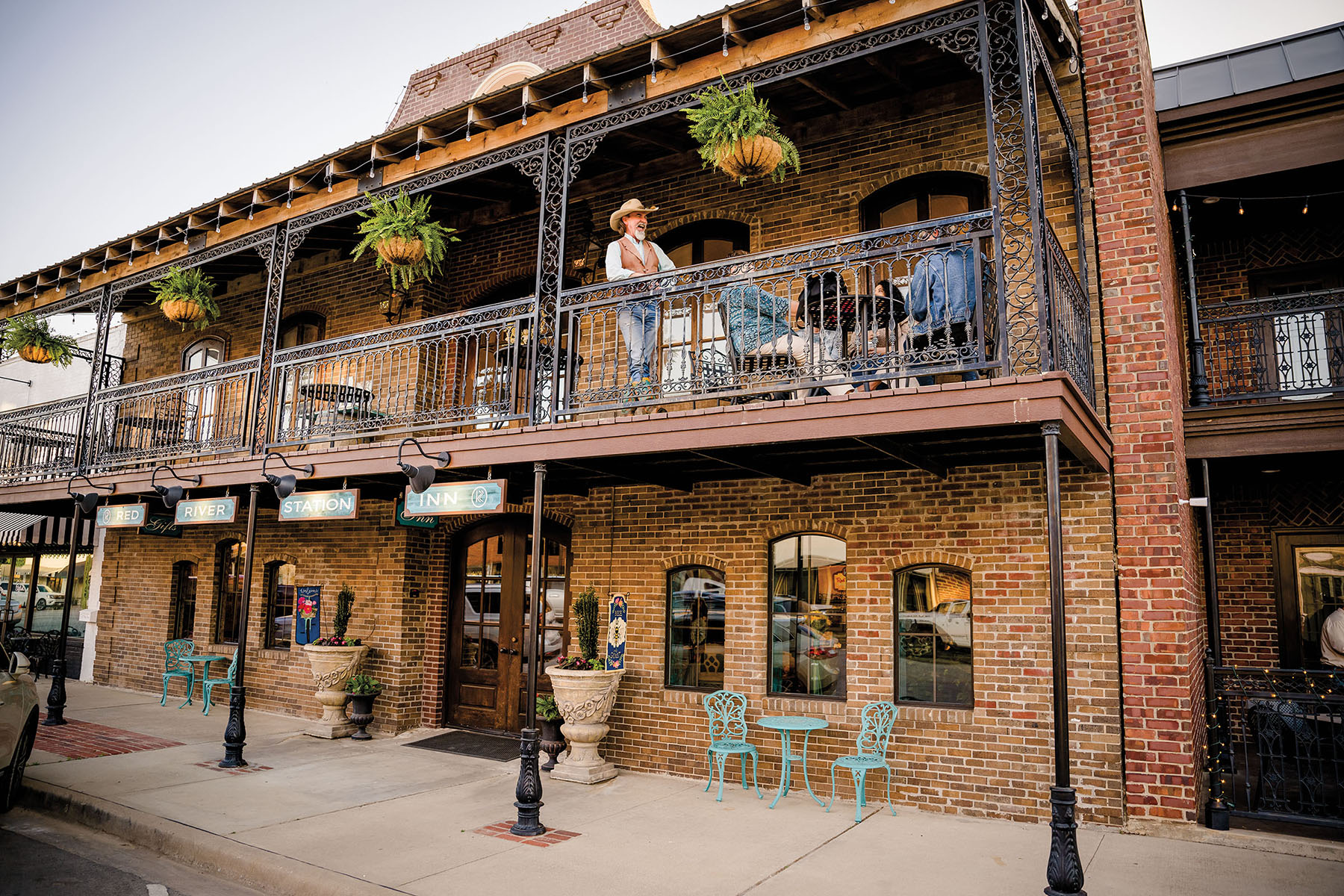 The exterior of a two-story brick building with people in western wear on the second story