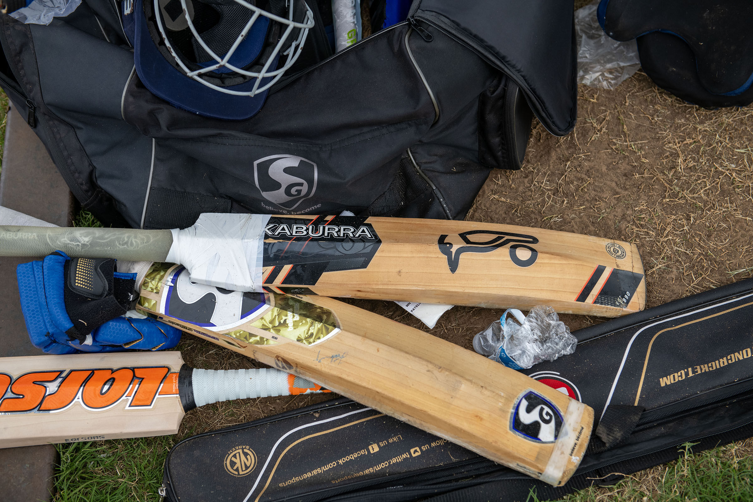 A pile of cricket equipment, including two bats