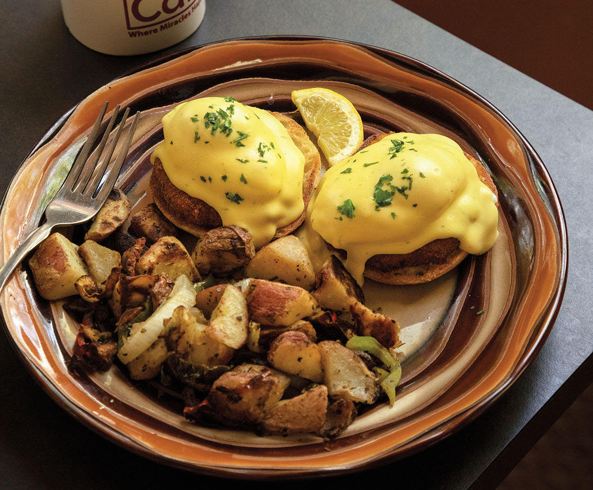 A platter of golden potatoes and eggs benedict with yellow hollandaise sauce