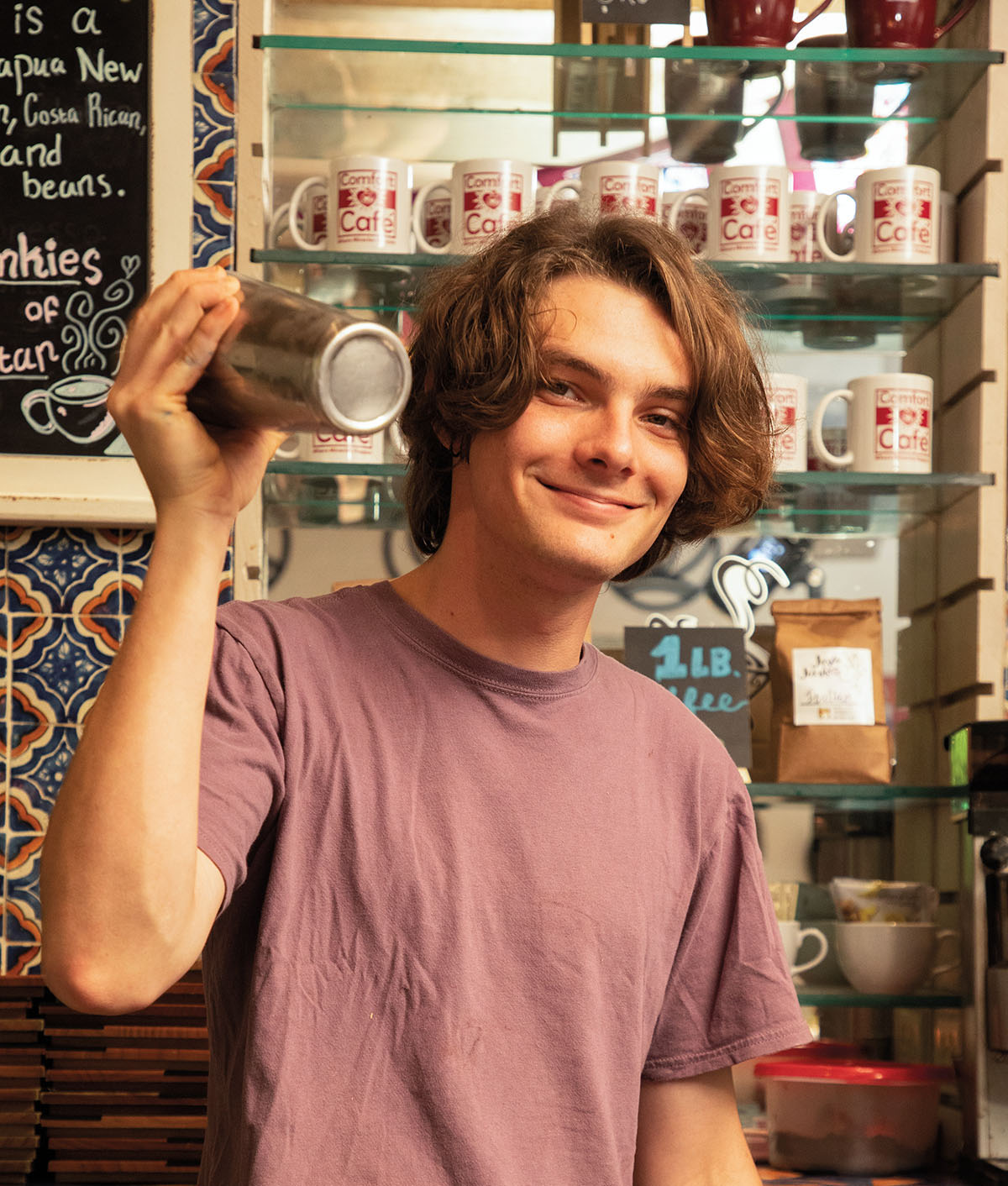 A young man in a t-shirt holds a metal shaker