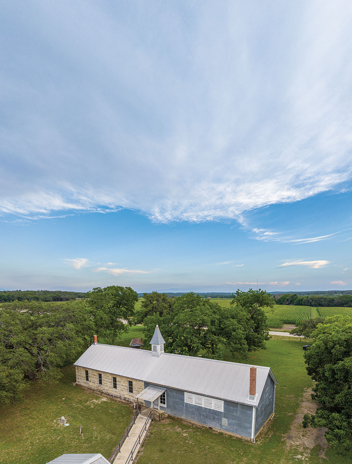 An overhead view of a metal and stone school building under a wide expanse of blue sky