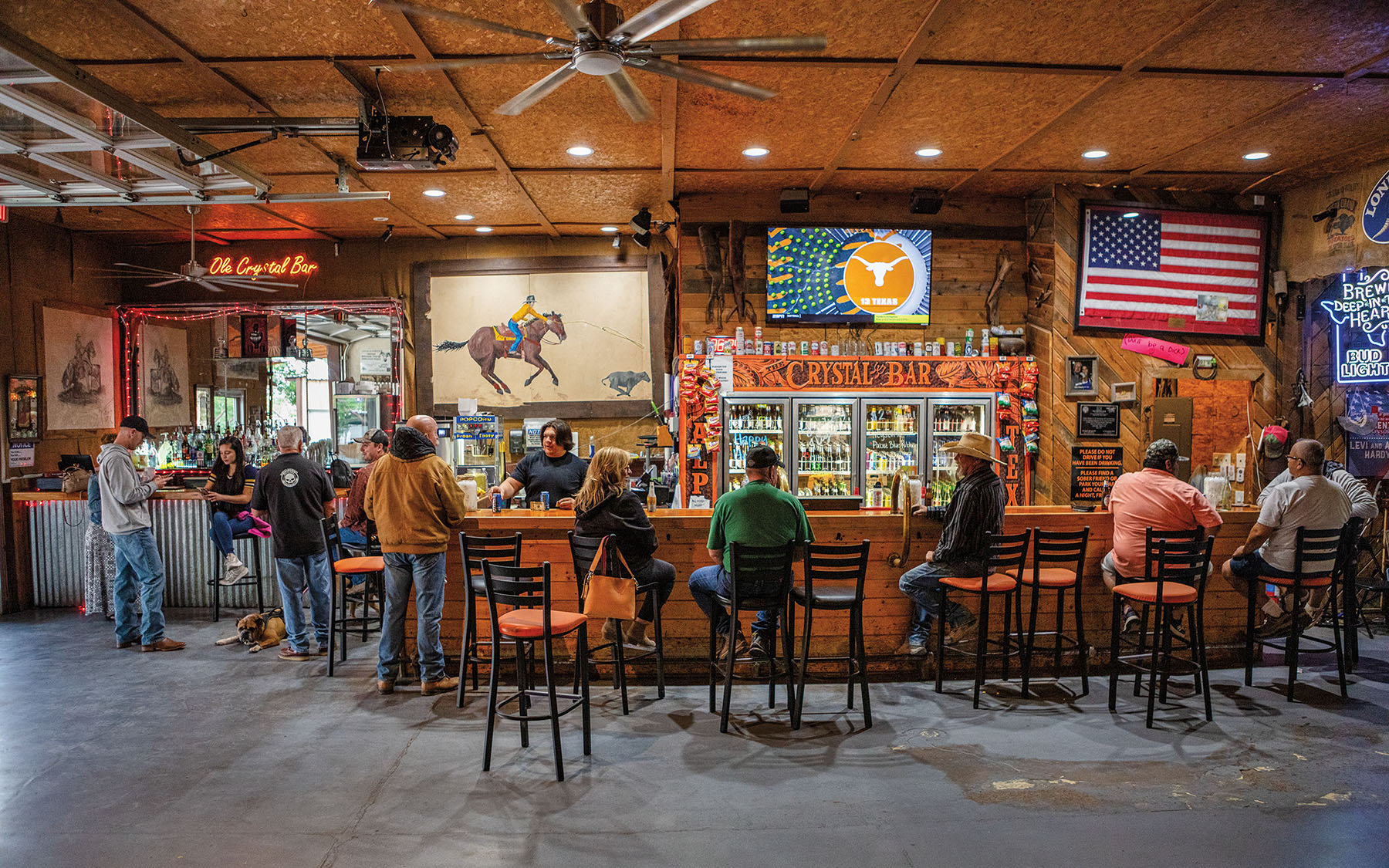 A group of people sit at a bar with wood-paneled ceiling and walls