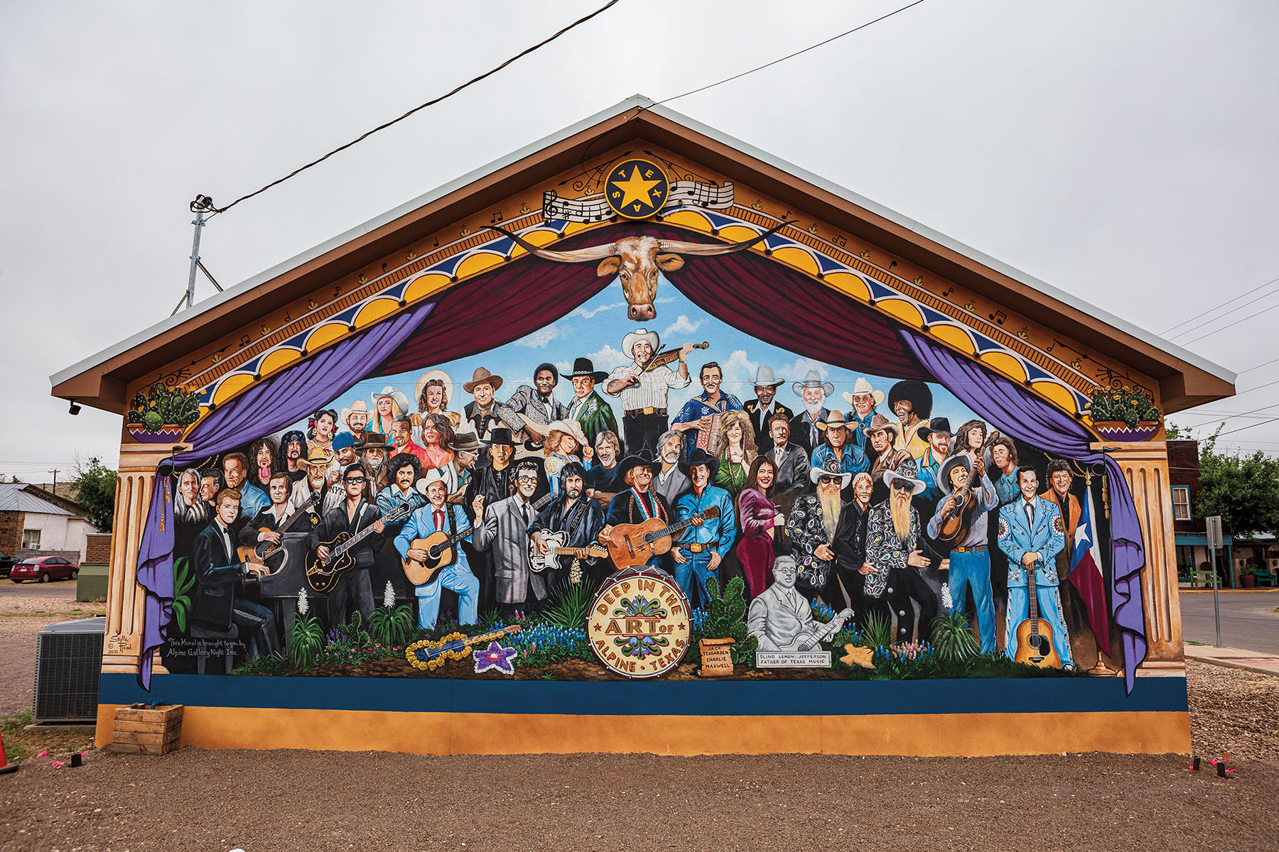 A brightly-colored painted mural of numerous famous Texas artists on a street corner