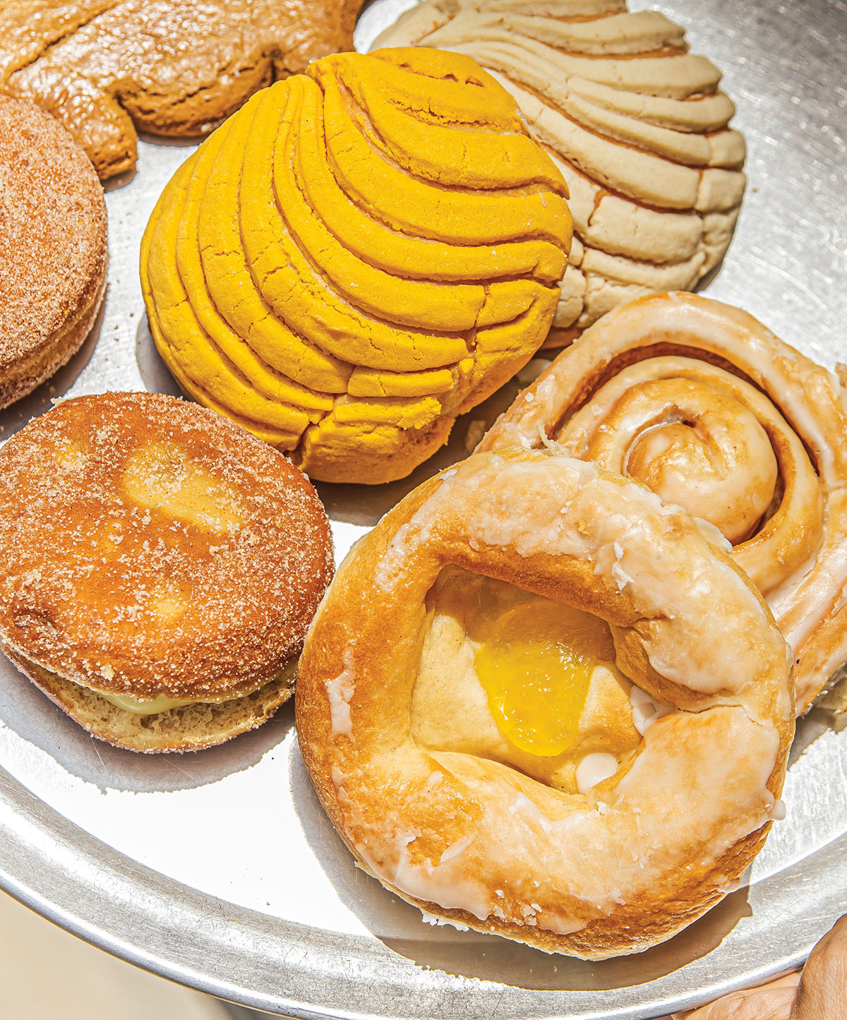 A collection of golden yellow pastries on a steel plate