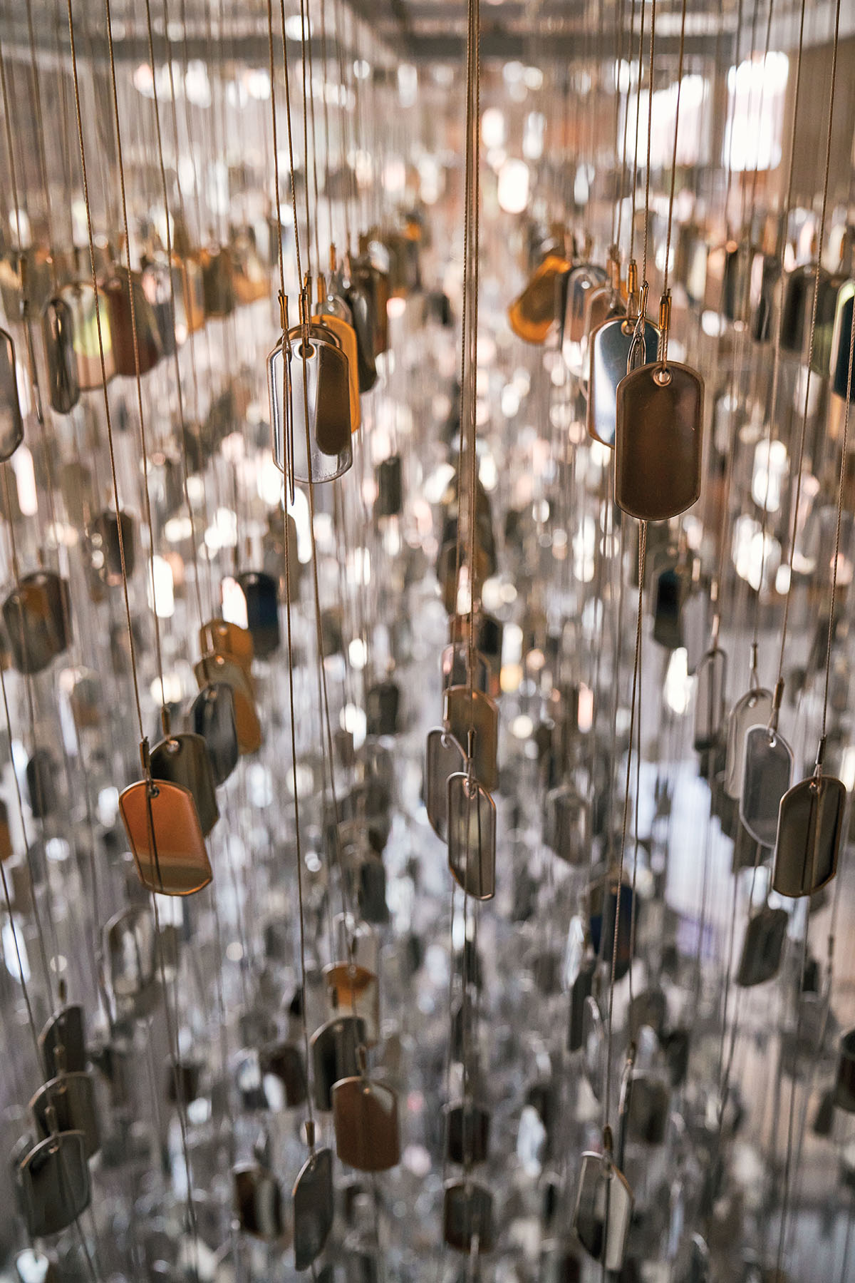 A large collection of reflective dog tags hang in front of a mirror