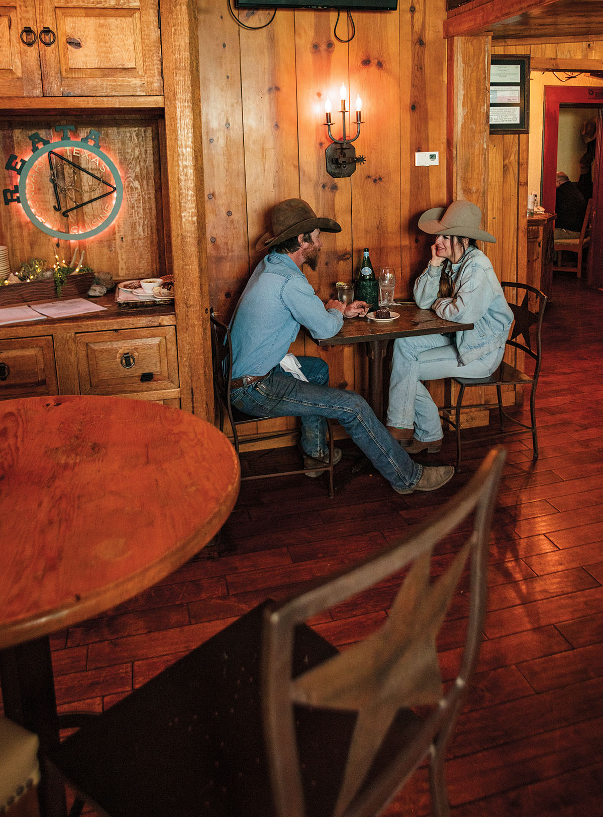 Two people wearing denim sit at a table in a wood-paneled restaurant
