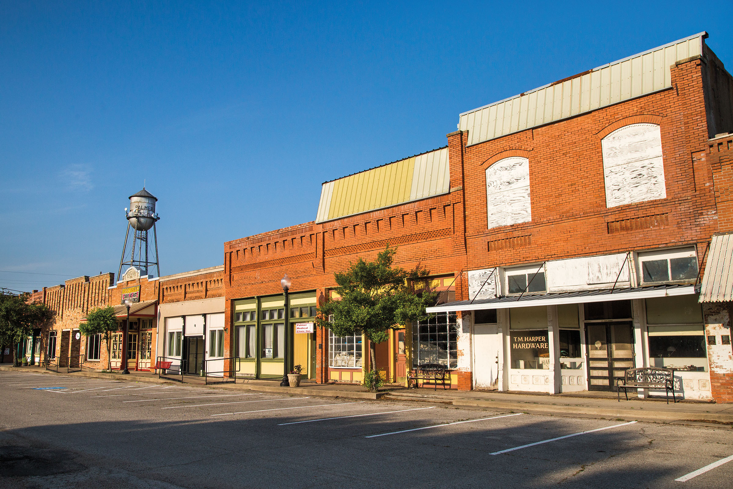The exterior of brick buildings along a historic main street with a large metal water tower
