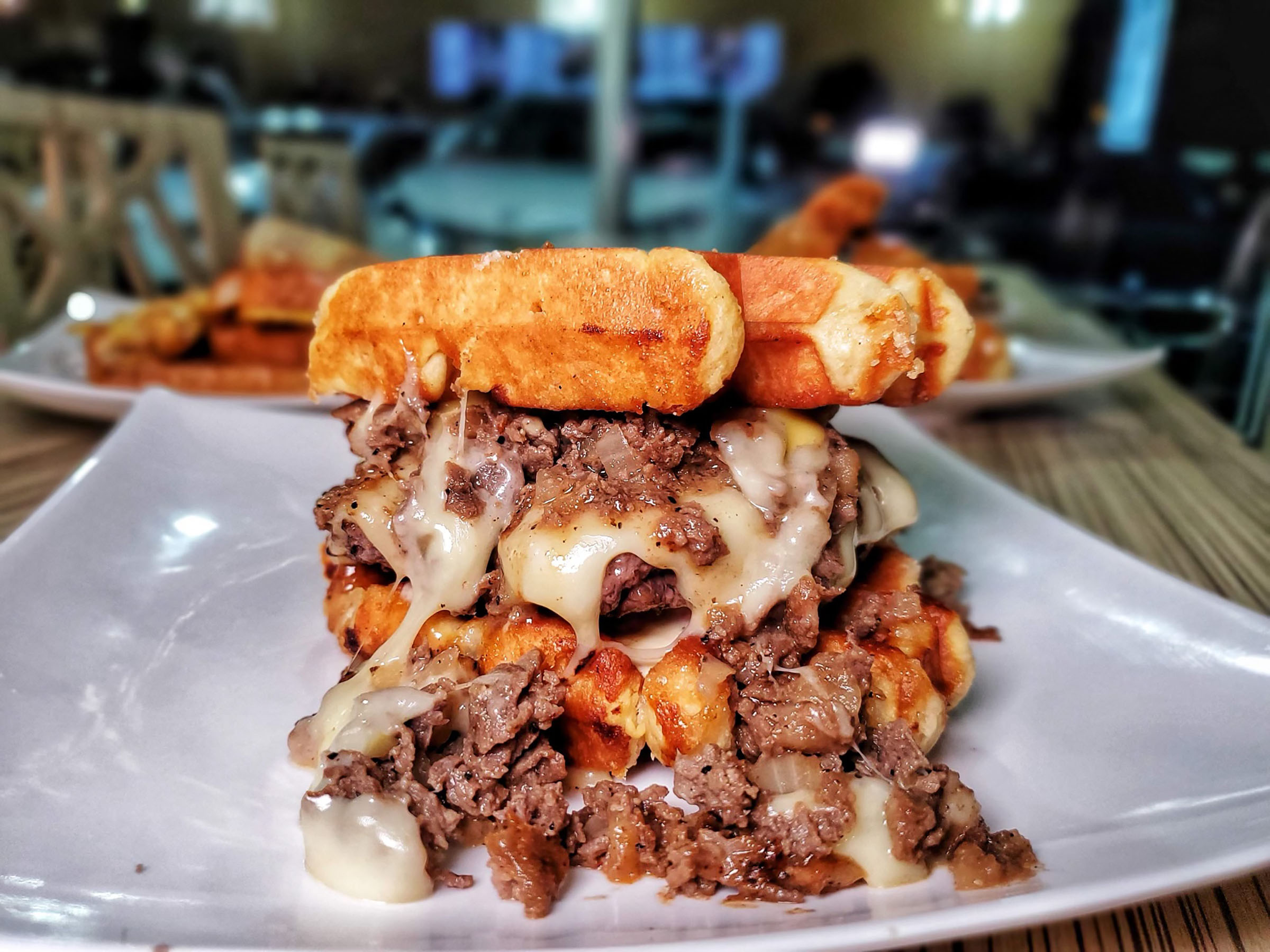 Two waffles piled high with a large portion of meat and cheese