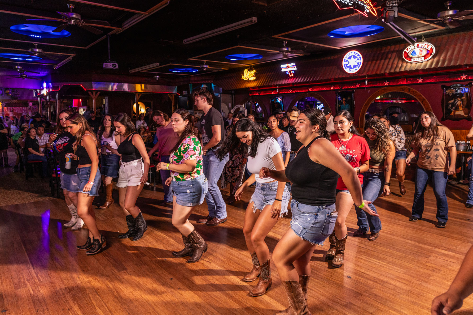 A group of young people dance on a wooden dance floor.