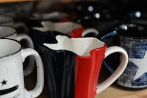 Red, white, and blue Texas-shaped mug, surrounded by Texas-themed mugs
