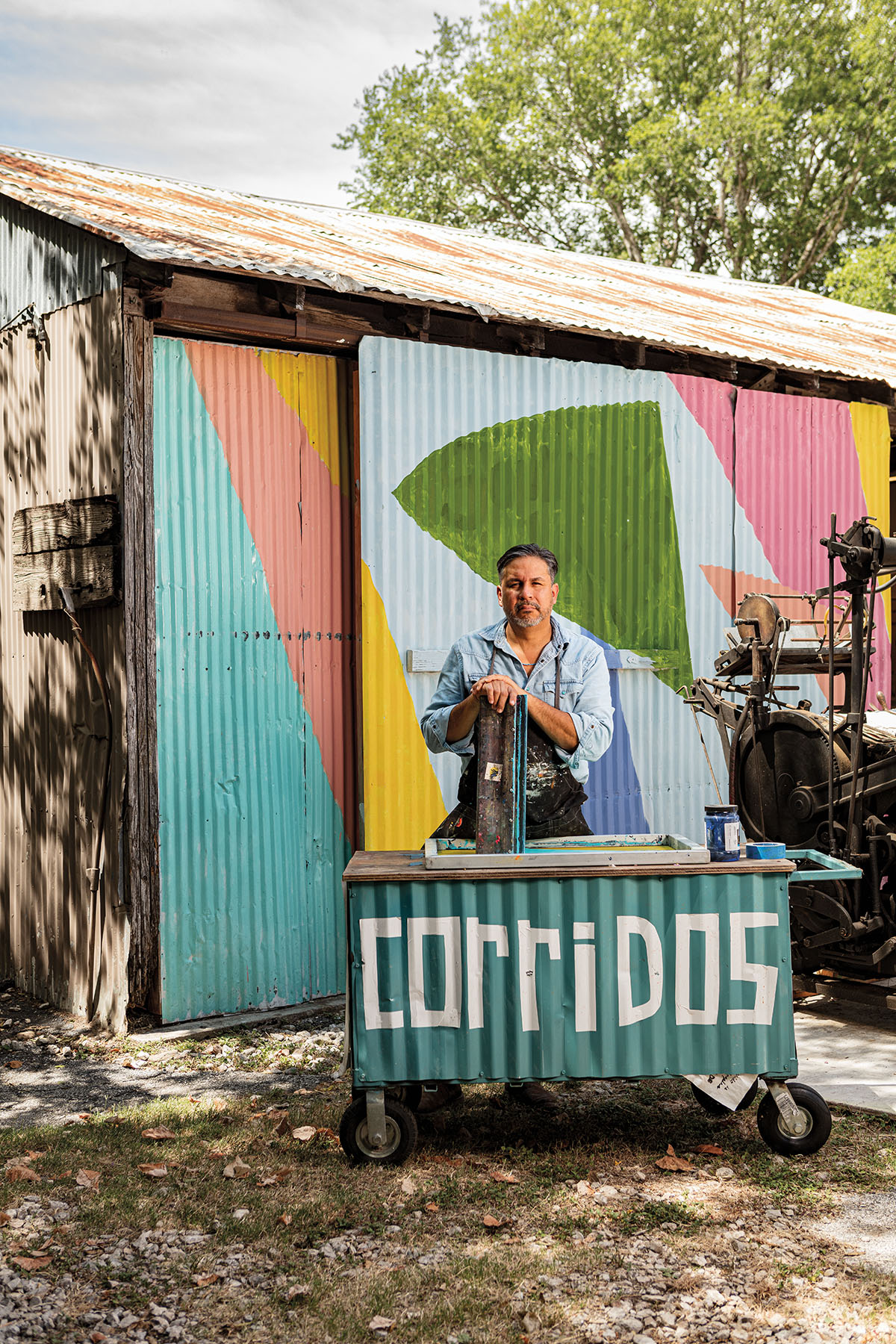 A man stands behind a teal metal sign reading 