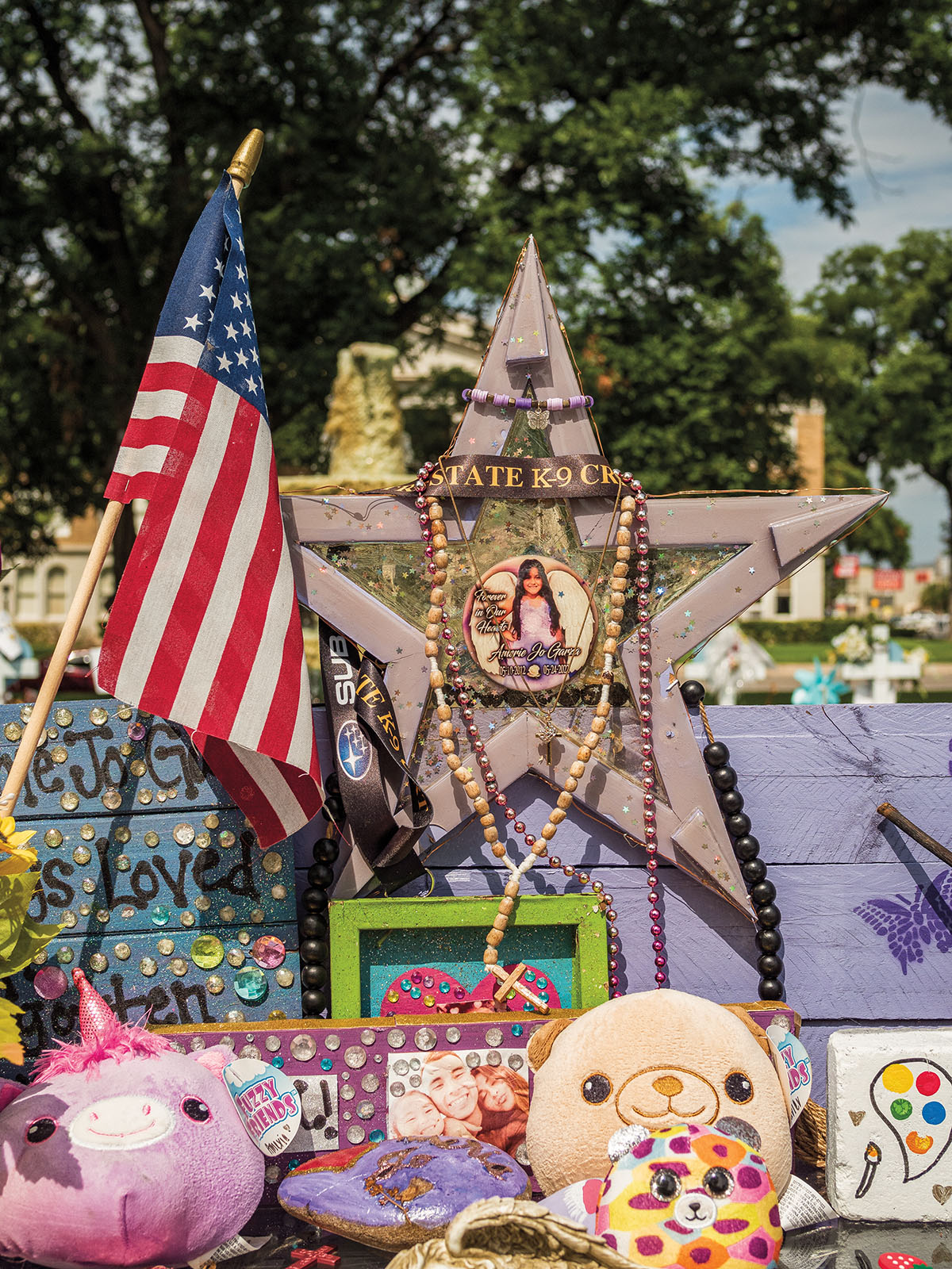 A closeup image of a shrine including an American flag, jewelry, a star, and photographs