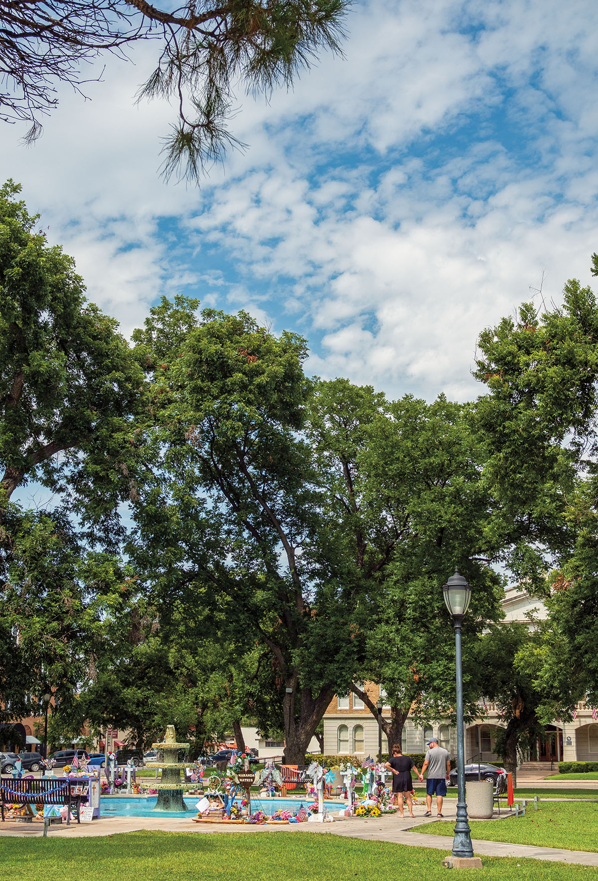 A view of the numerous shrines on display in a town square setting beneath green trees and blue sky