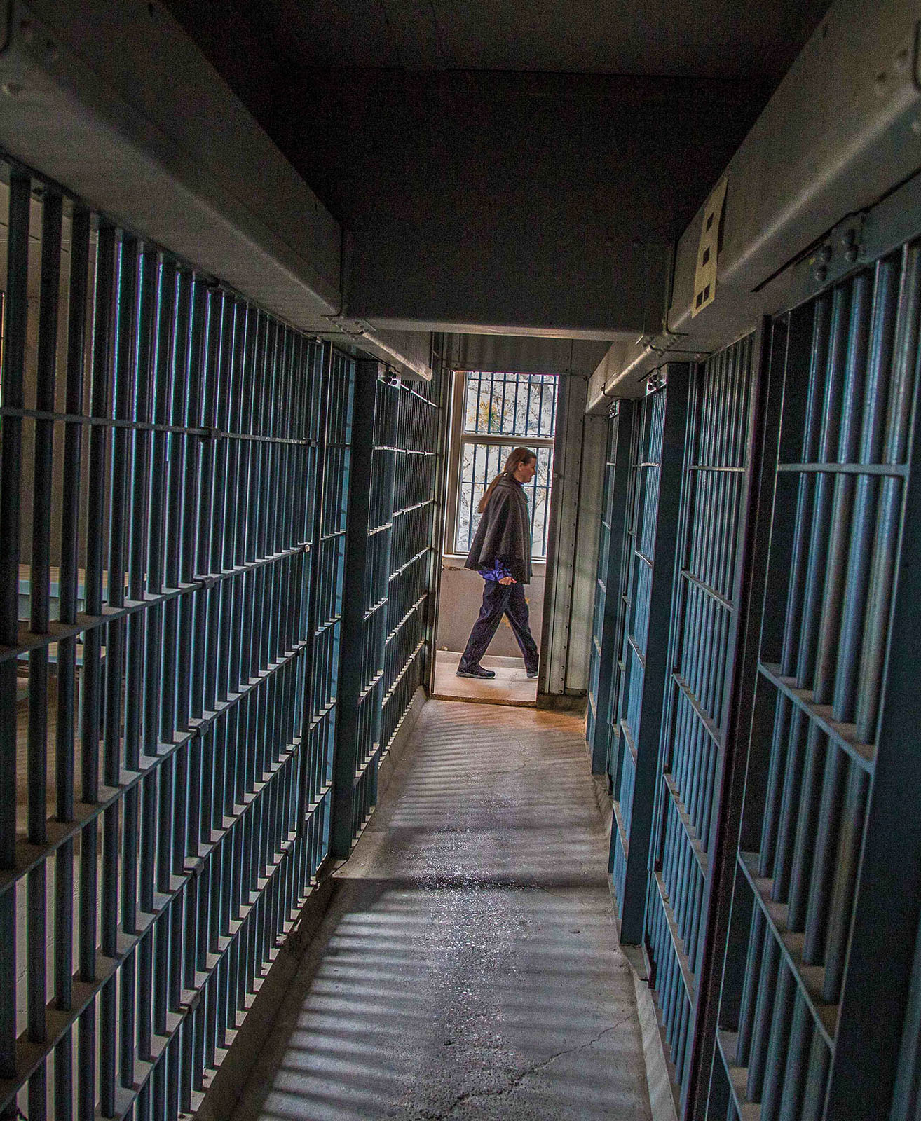 A person walks down a hallway of jail cells