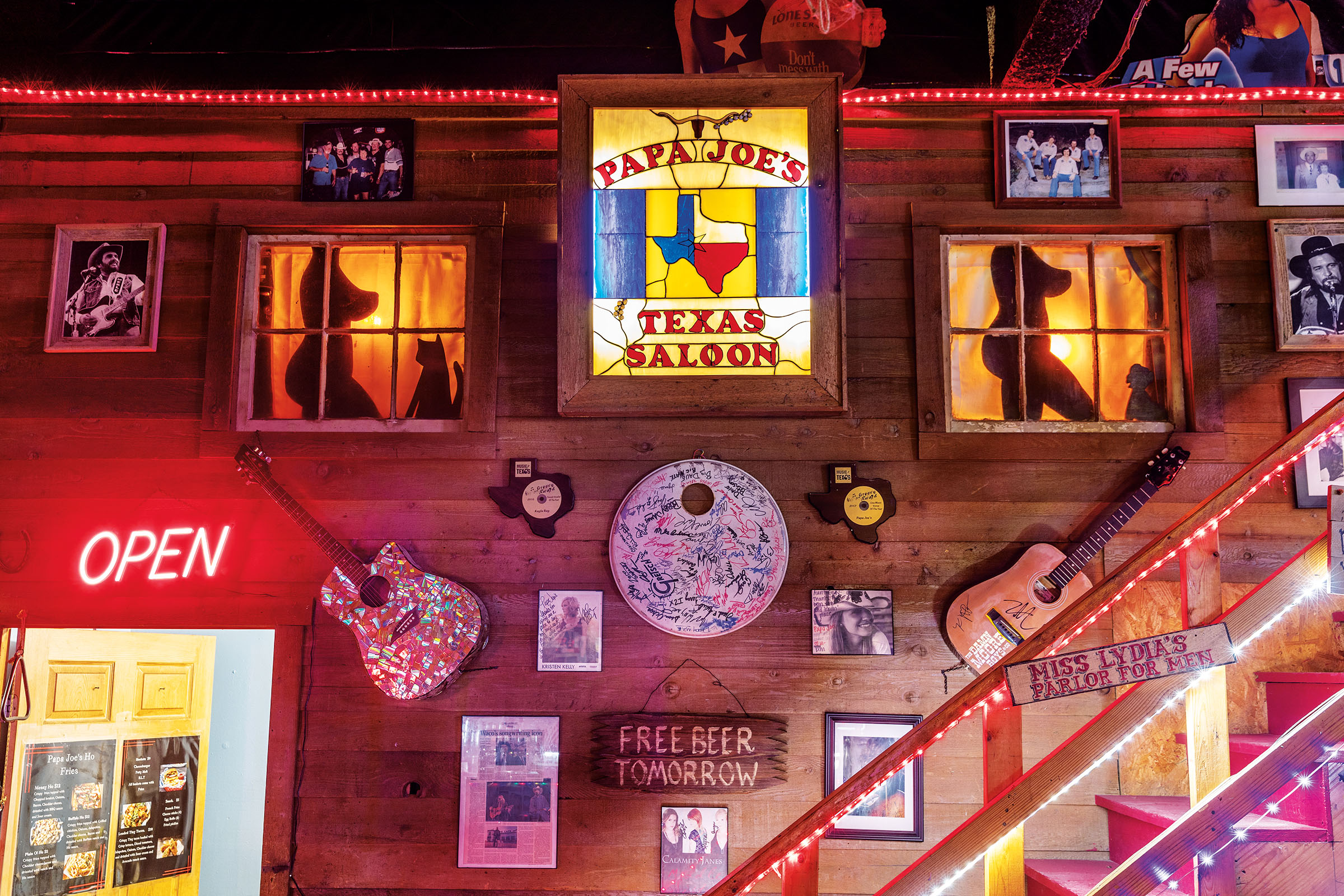 The wall of a saloon with large neon signs, lighted windows and memorabilia
