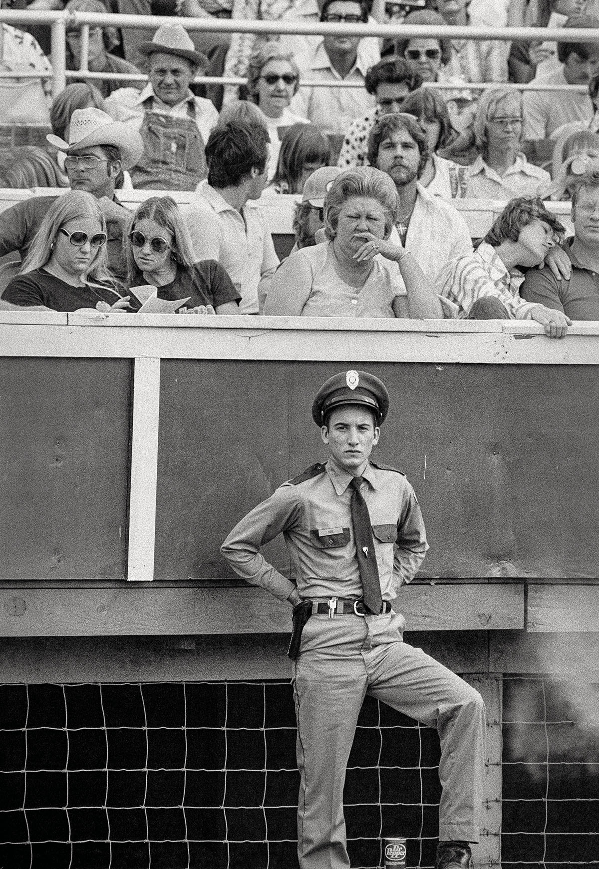 A police officer in his uniform stands in front of a crowd of seated spectators