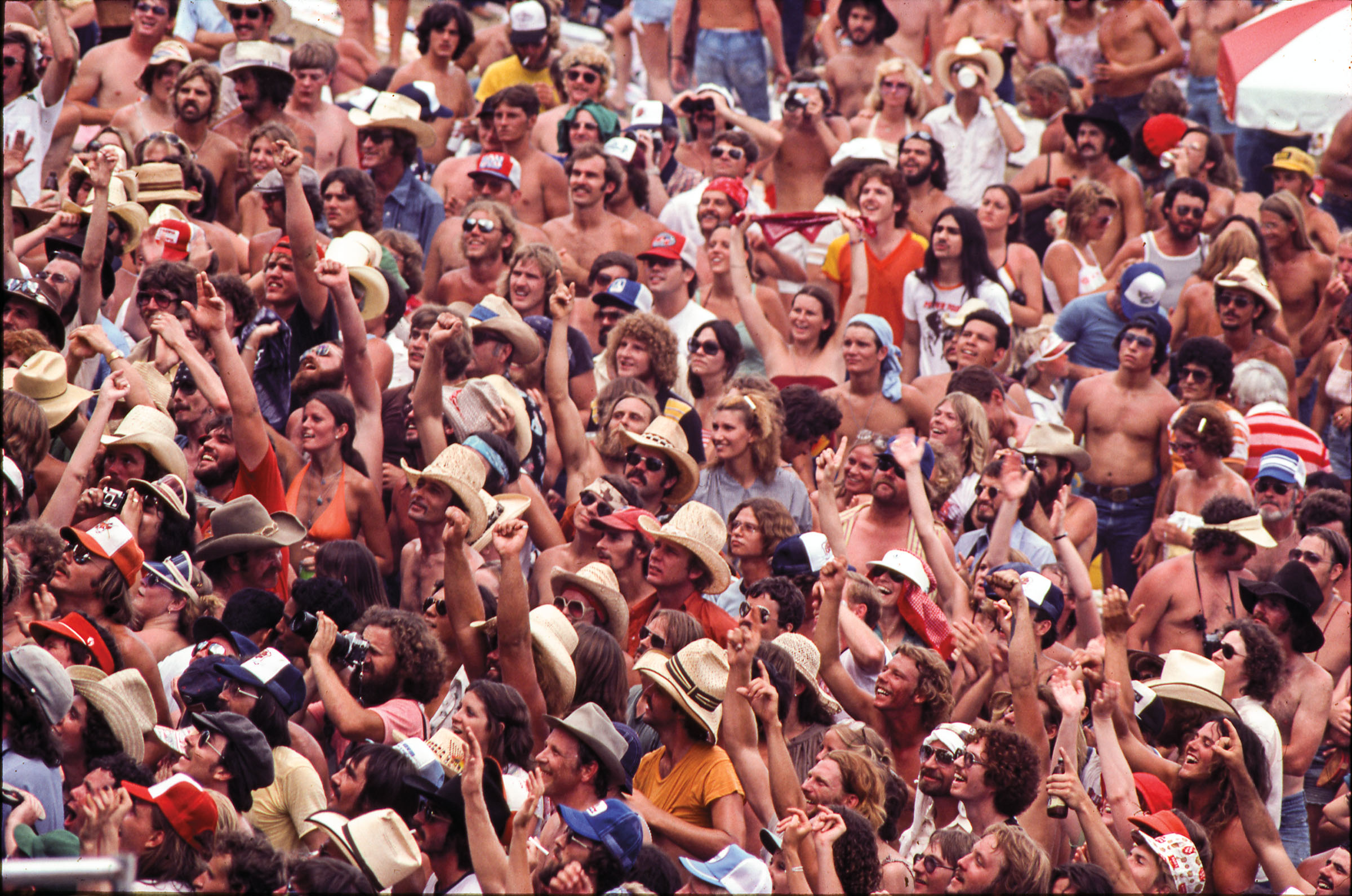 Large crowd of people with their hands up.