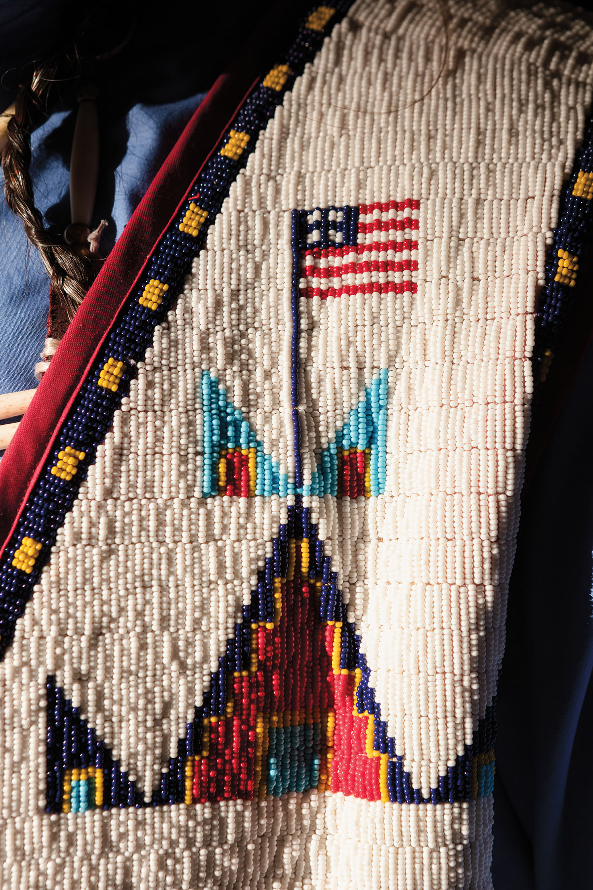 A closeup photograph of intricate beadwork, including a depiction of the American flag