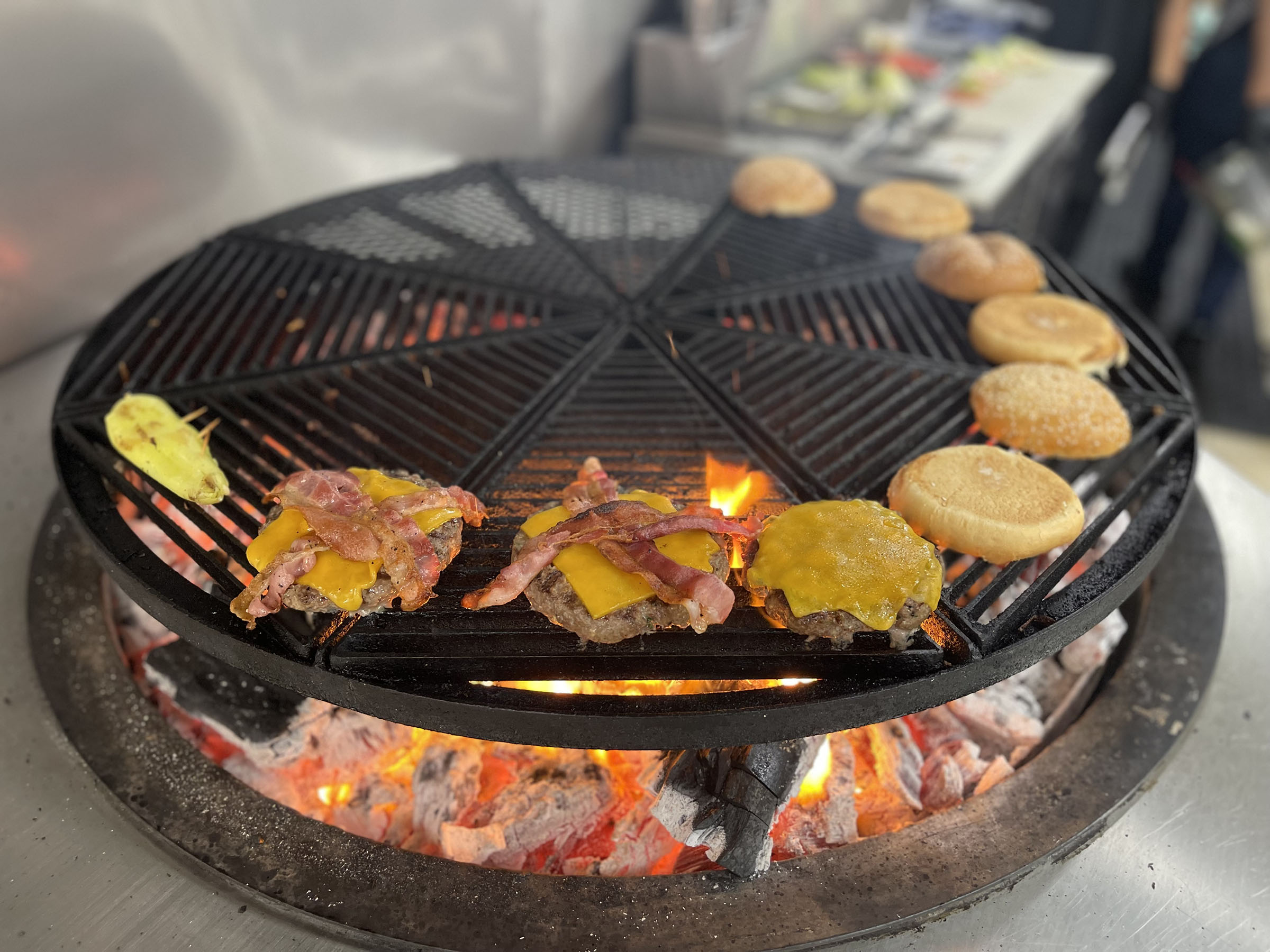 color photo of circular grill with burgers