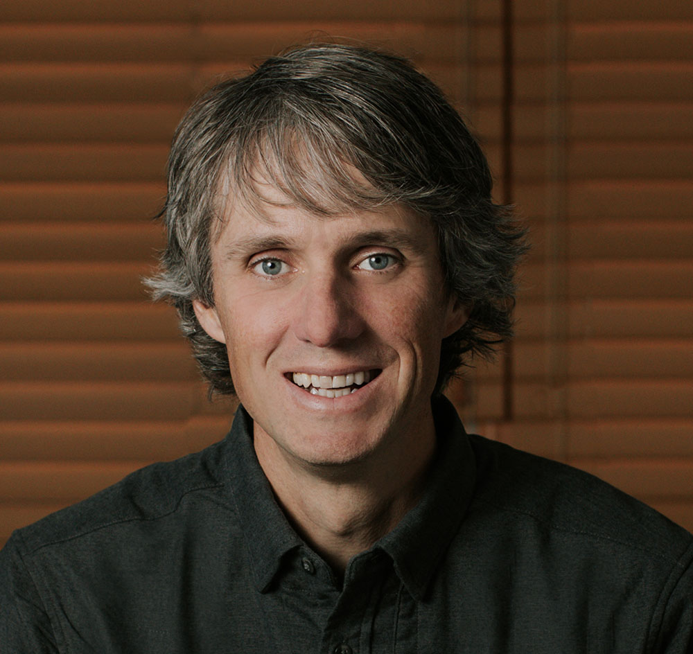 A portrait of a man wearing a black button-up shirt