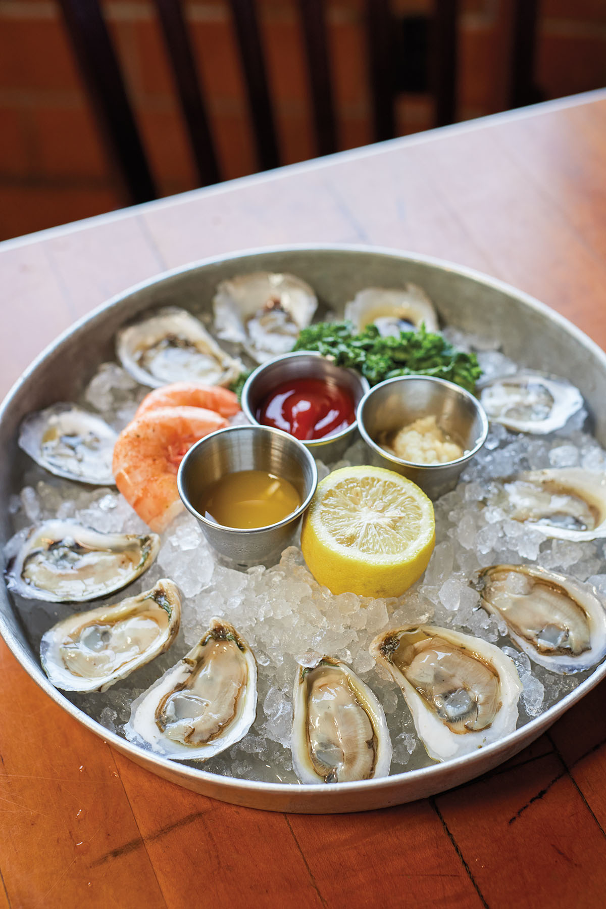 A platter of oysters on the half-shell on a plate with sauces and ice