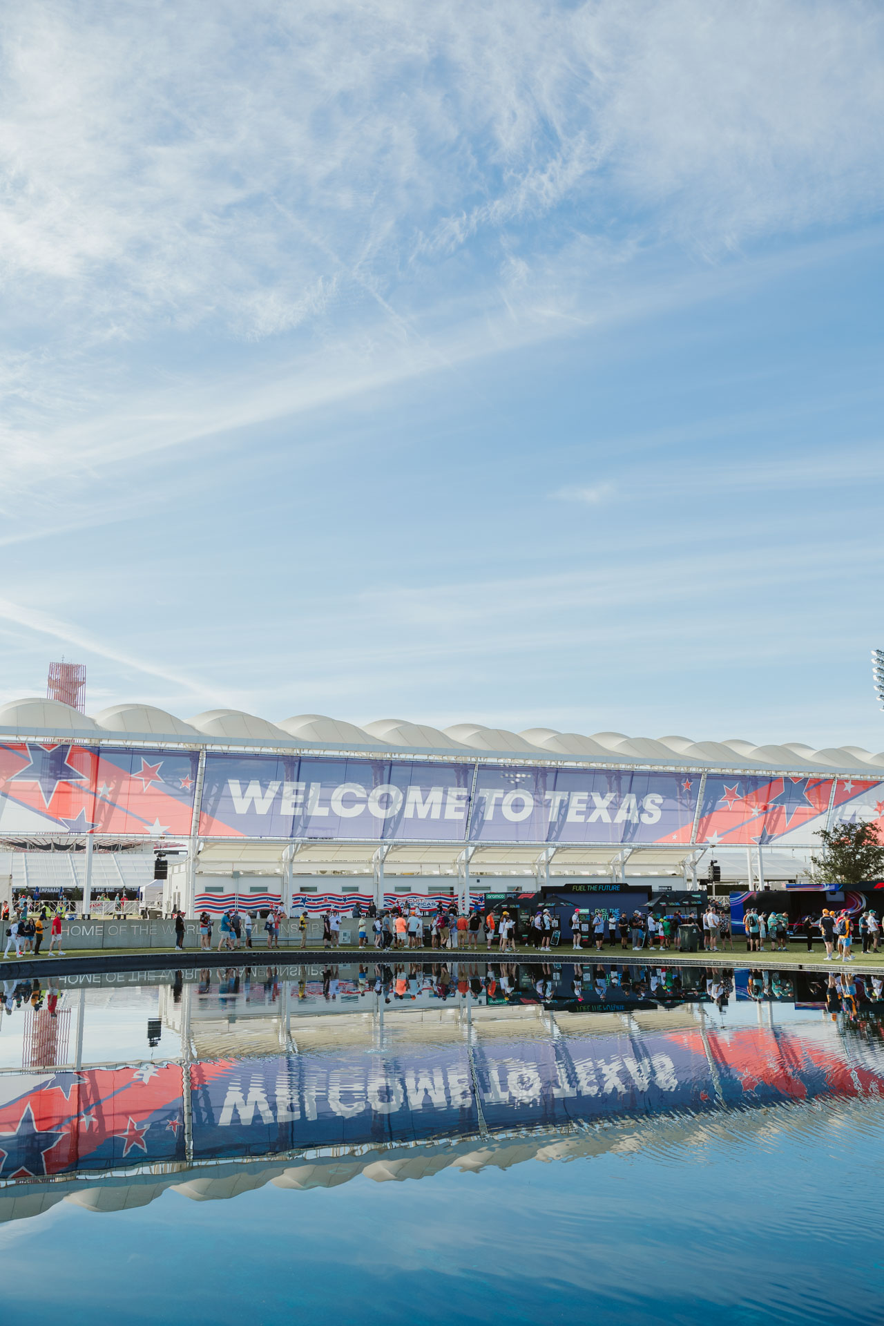 A large banner reading 'Welcome to Texas' reflected in a large pool on the F1