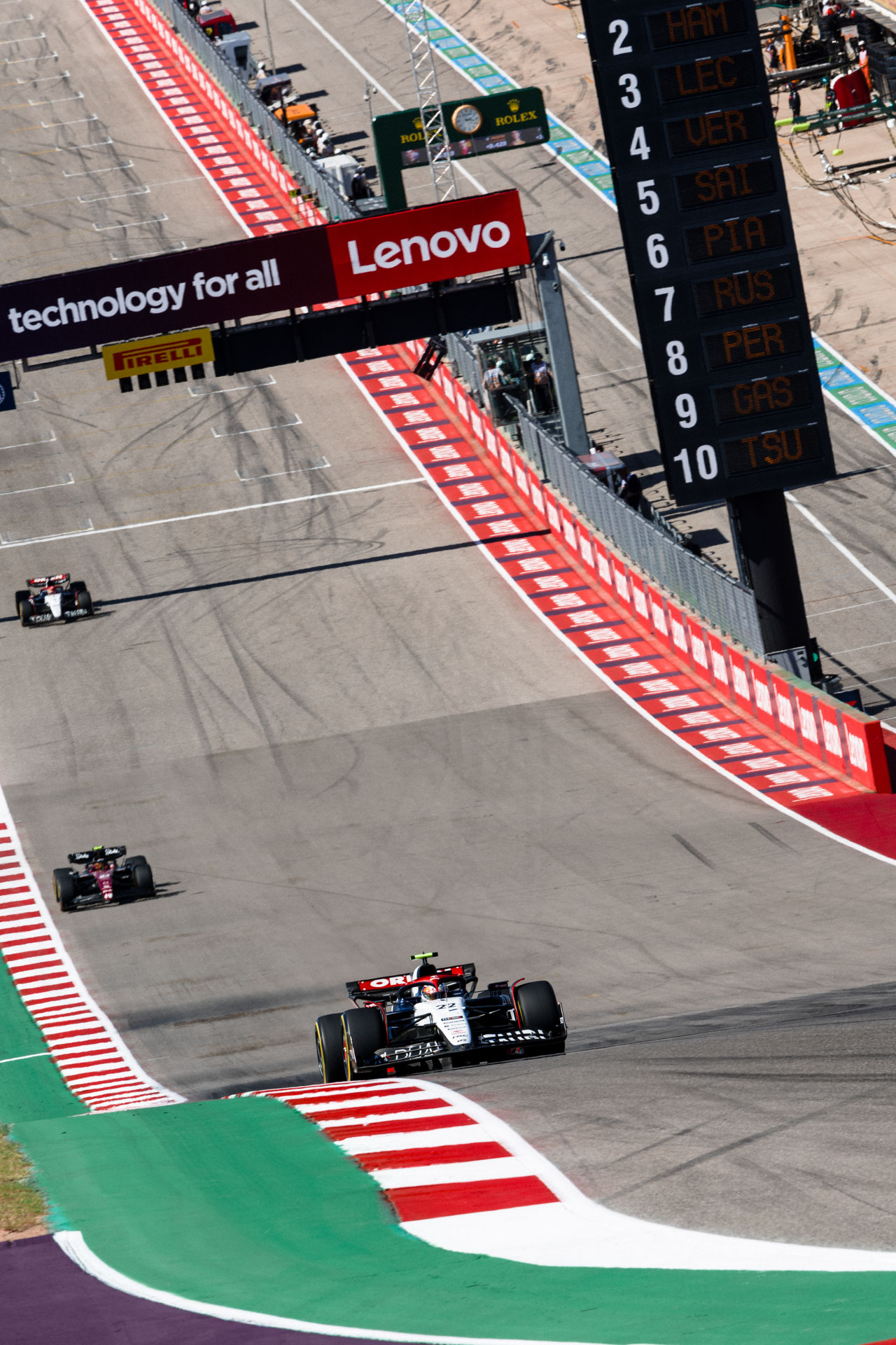 An overhead view of an F1 car coming down a slightly hilly pavement course