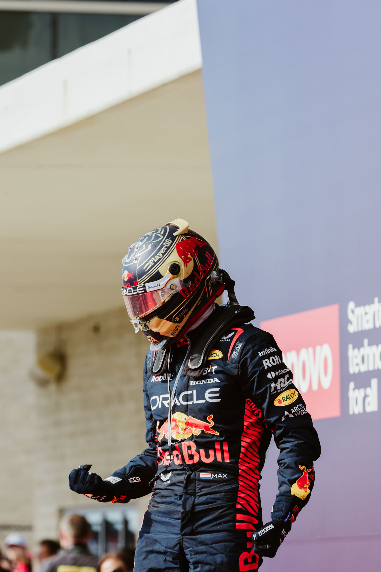 A person in a race helmet and Red Bull Racing uniform makes a celebratory pose