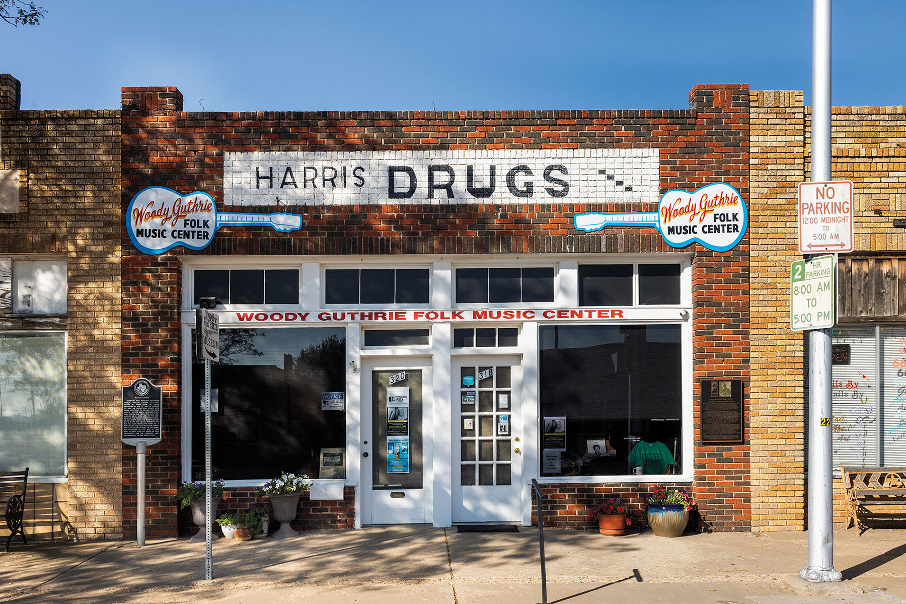 The exterior of a brick building with a sign reading "Harris Drugs" and paintings of guitars above the door