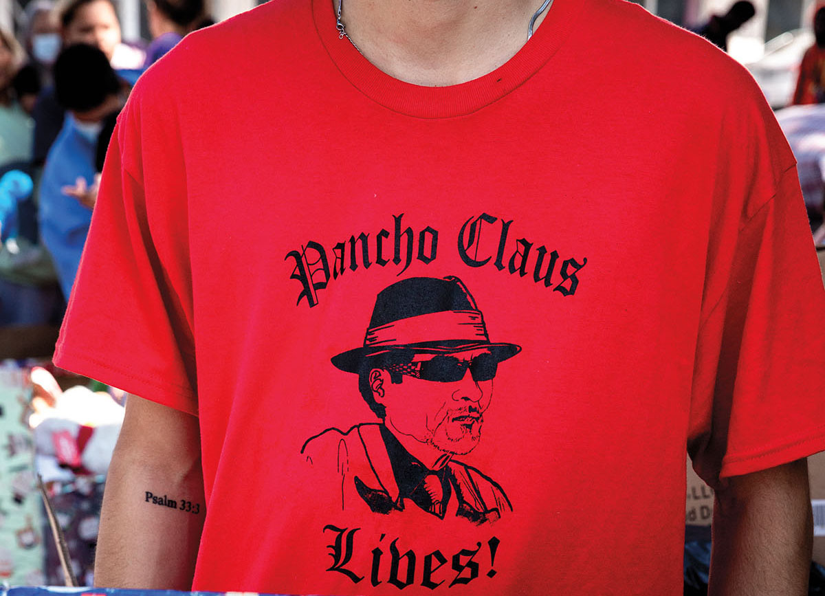 A person wearing a bright red shirt with black lettering reading "Pancho Claus Lives"