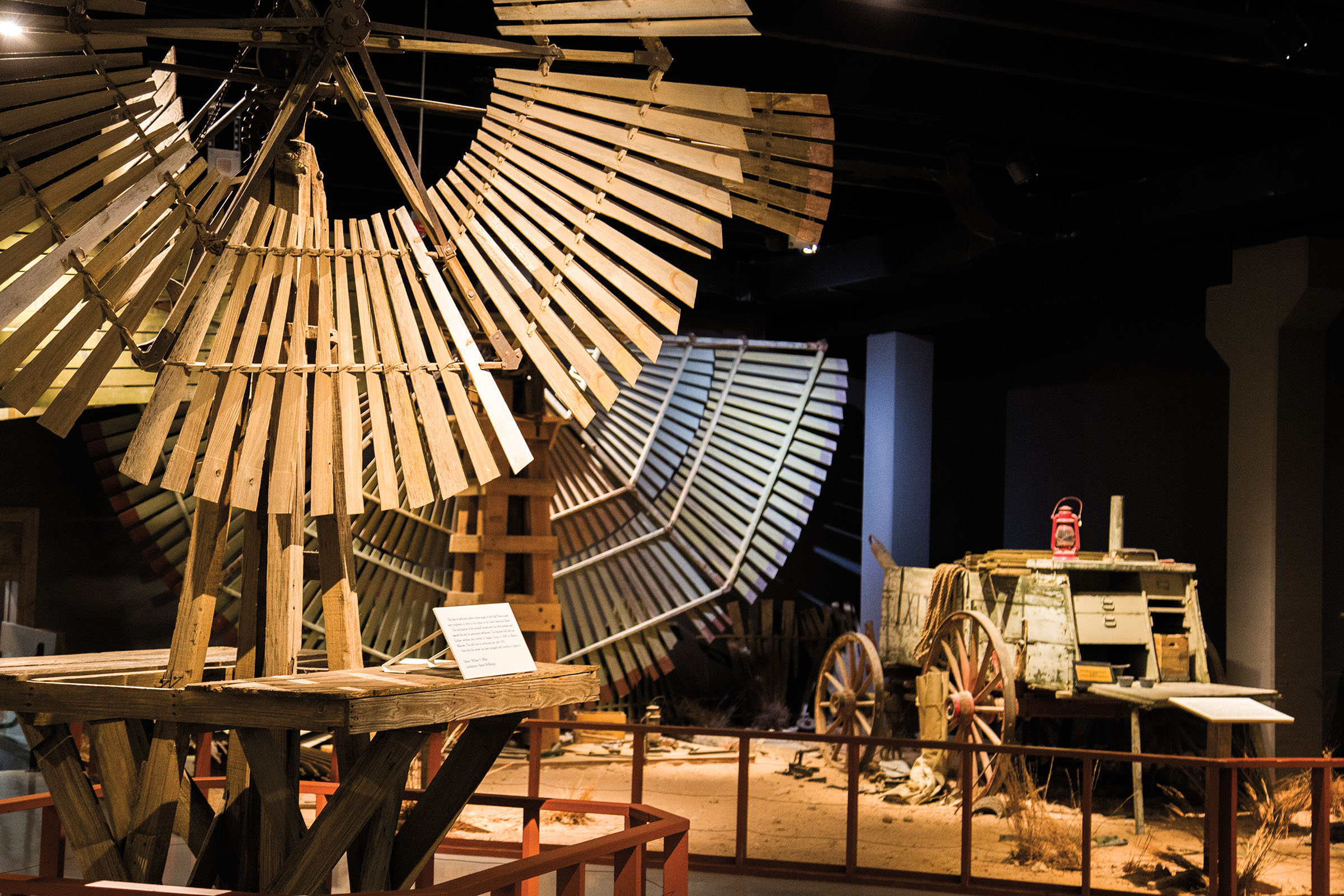 A collection of wooden windmills inside of a museum. 