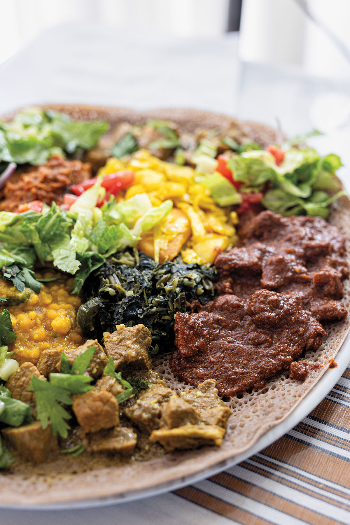 A platter of brightly colored foods and vegetables on a striped placemat