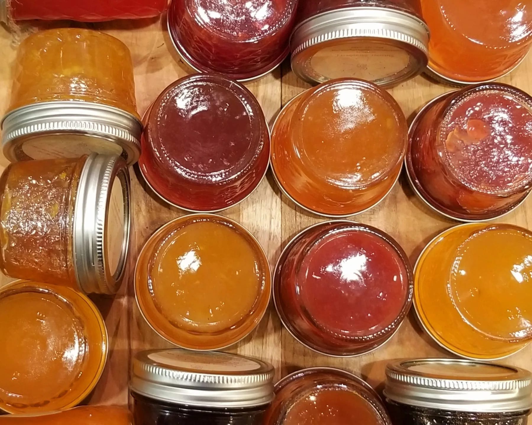 Red, orange, and yellow jellies in small jars laying on a table